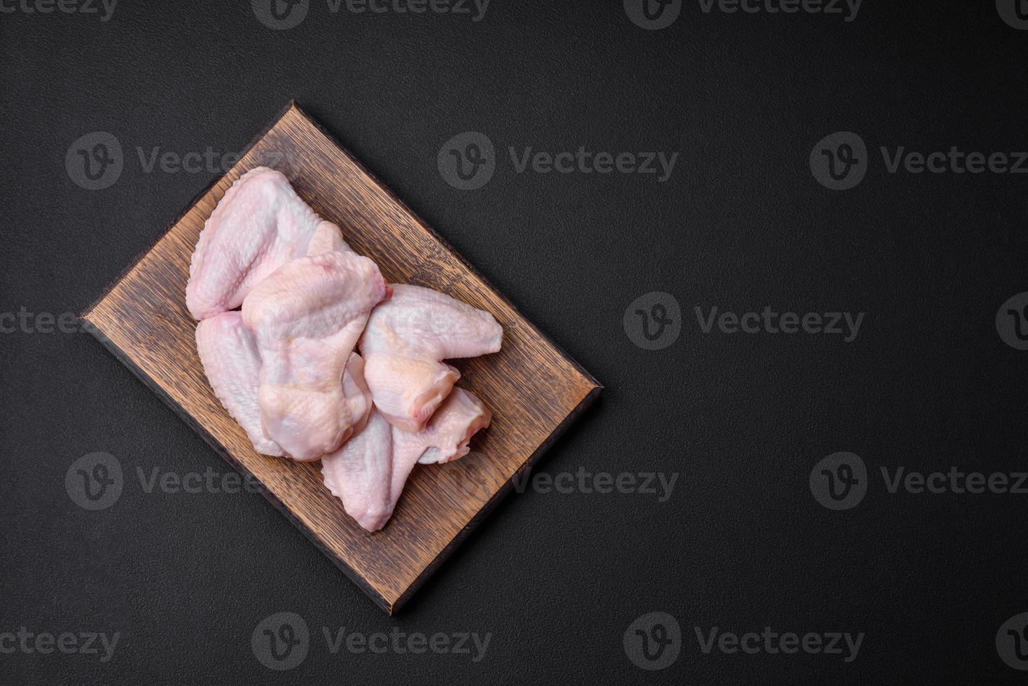 Raw chicken wings with salt, spices and herbs on a wooden cutting board photo