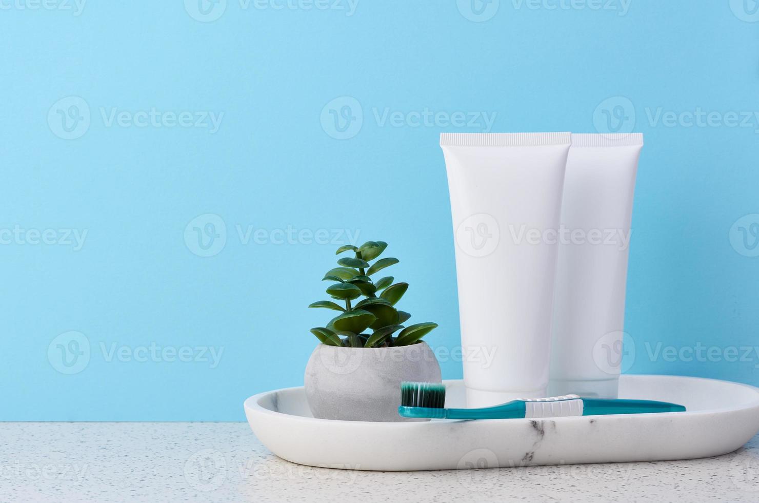 White plastic toothpaste tube and toothbrush on a bluek background photo