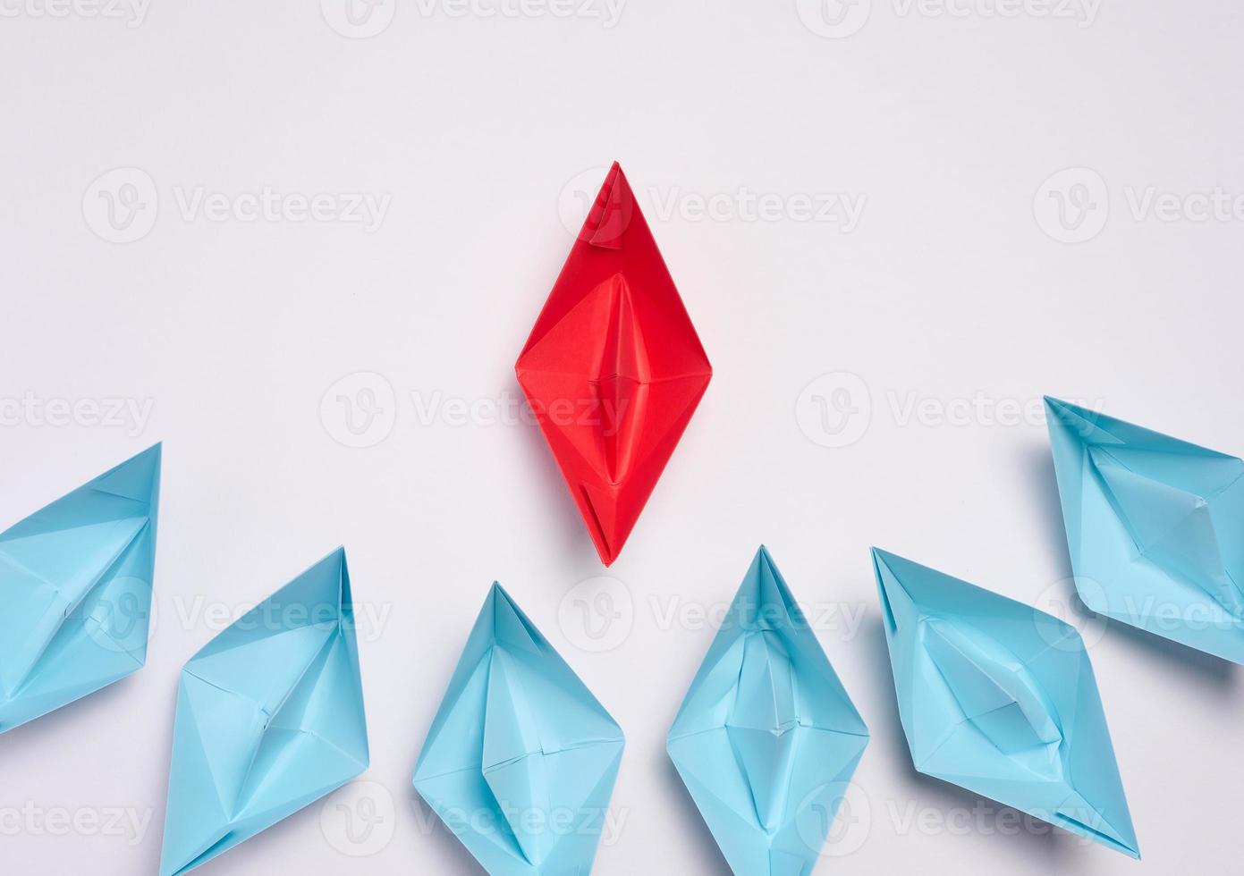 A group of blue paper boats surrounded one red boat, the concept of bullying, search for compromise. Top view photo