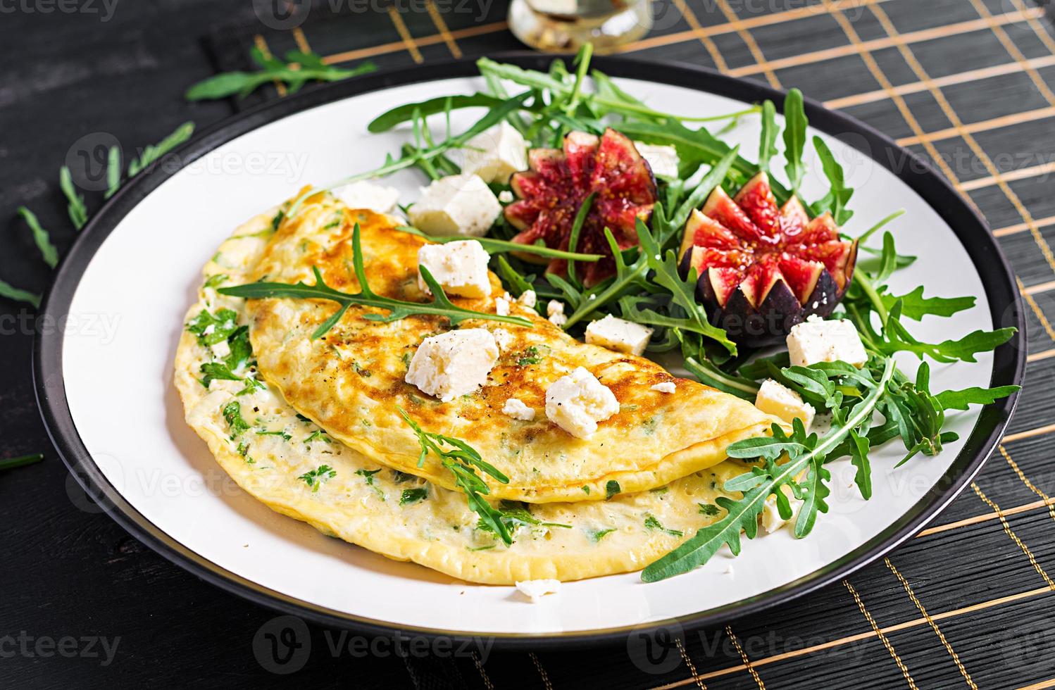 tortilla con queso feta queso, perejil y ensalada con higos, Rúcula en blanco lámina. frittata - italiano tortilla. foto