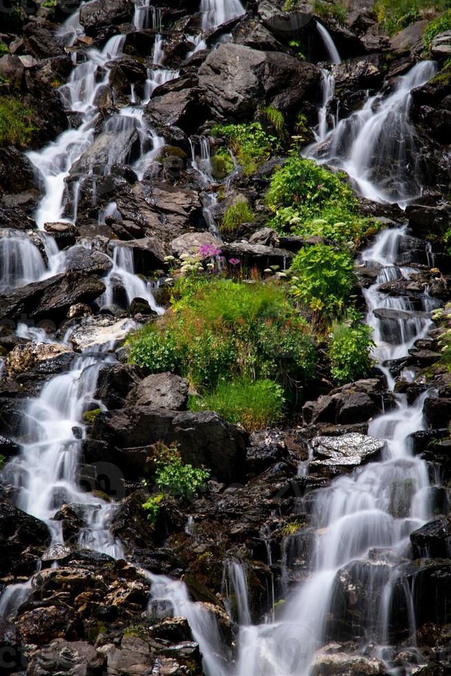 A waterfall surrounded by green grass photo