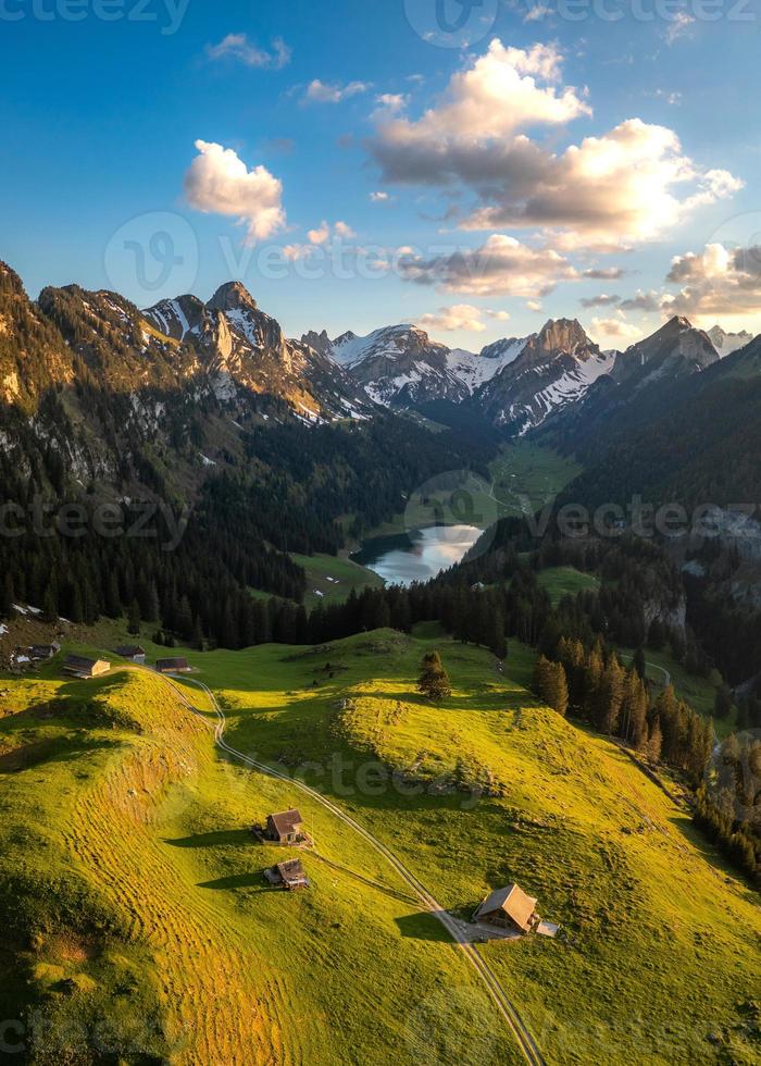 A farm in the valley next to a mountain lake photo