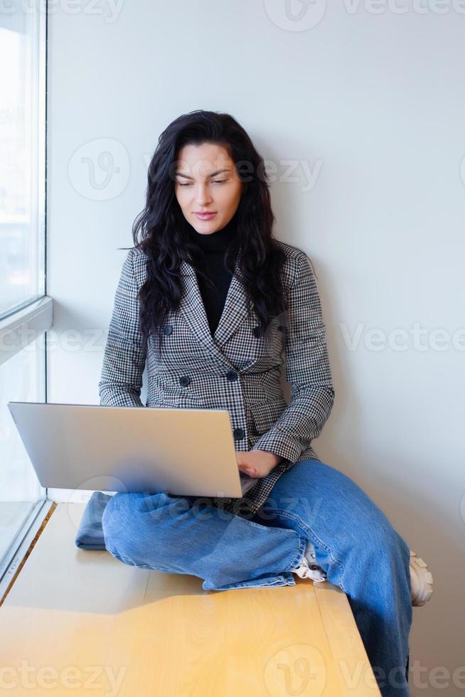 Beautiful businesswoman working on a laptop. Female freelancer connecting to internet via computer. Blogger or journalist writing new article. photo