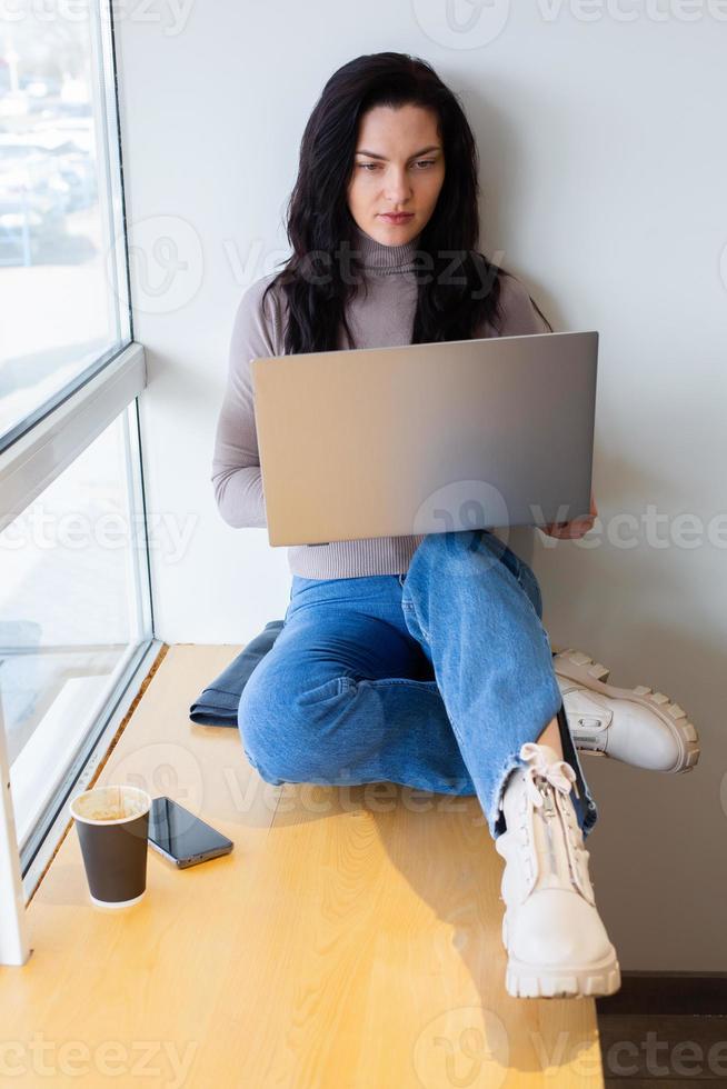 Beautiful businesswoman working on a laptop. Female freelancer connecting to internet via computer. Blogger or journalist writing new article. photo