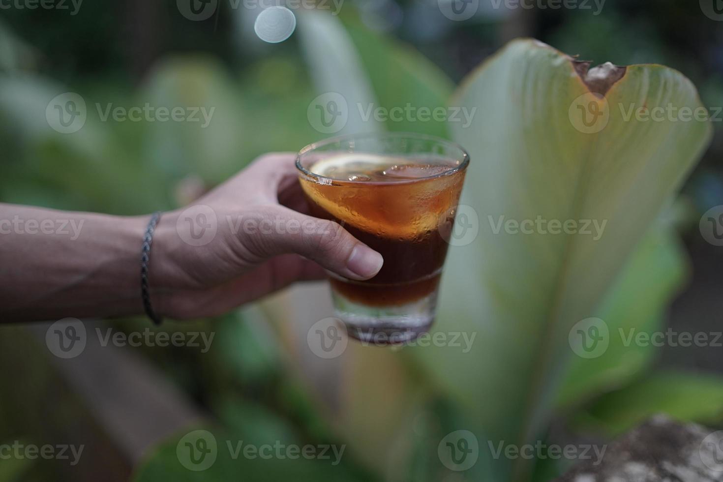 con hielo café limón en mano con verdor antecedentes. foto