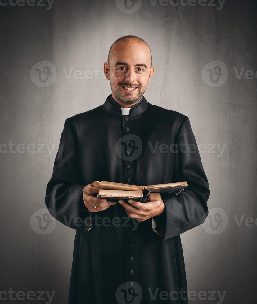 sacerdote sonriente y participación un Biblia foto