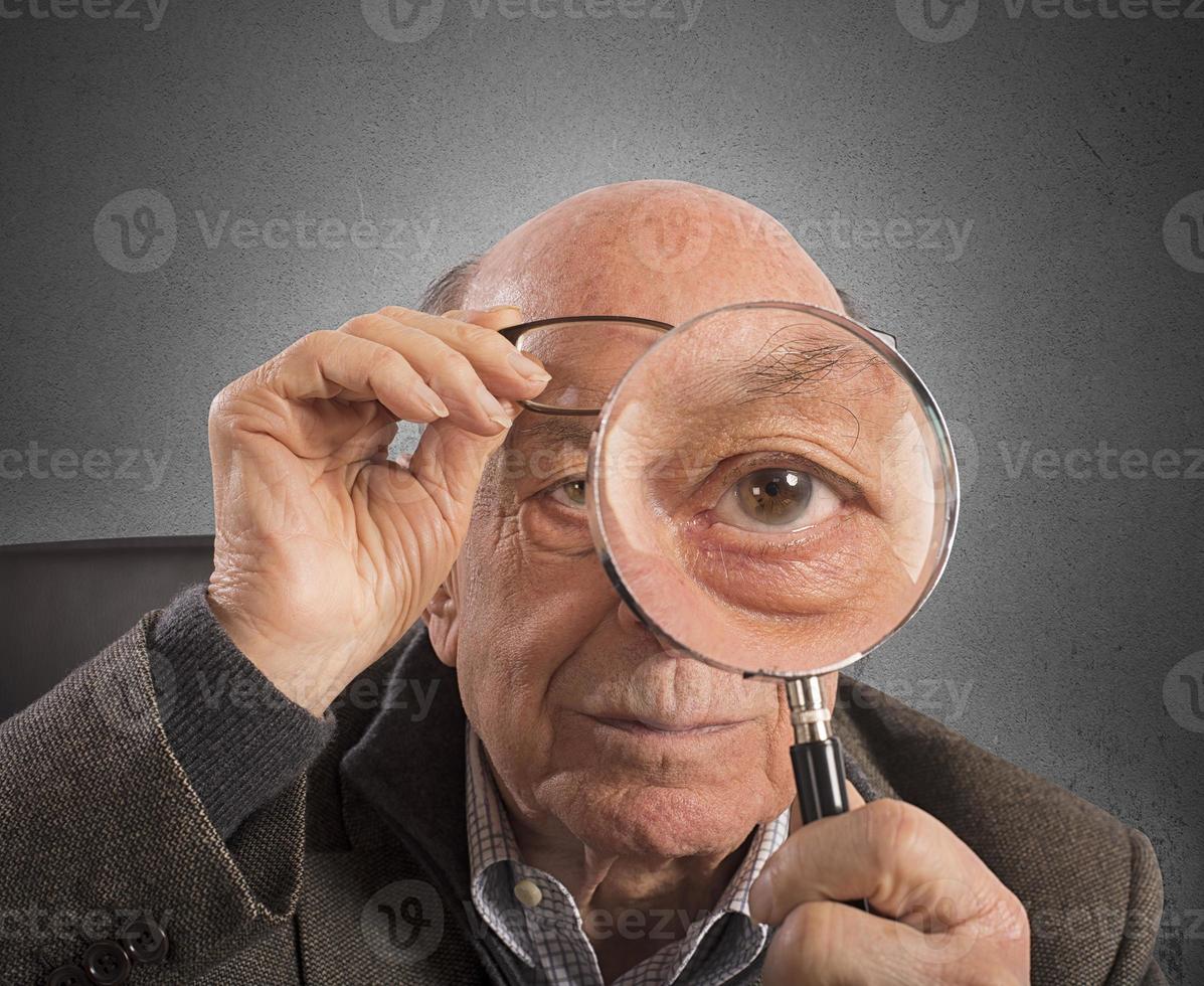 Elder man with magnifying glass photo