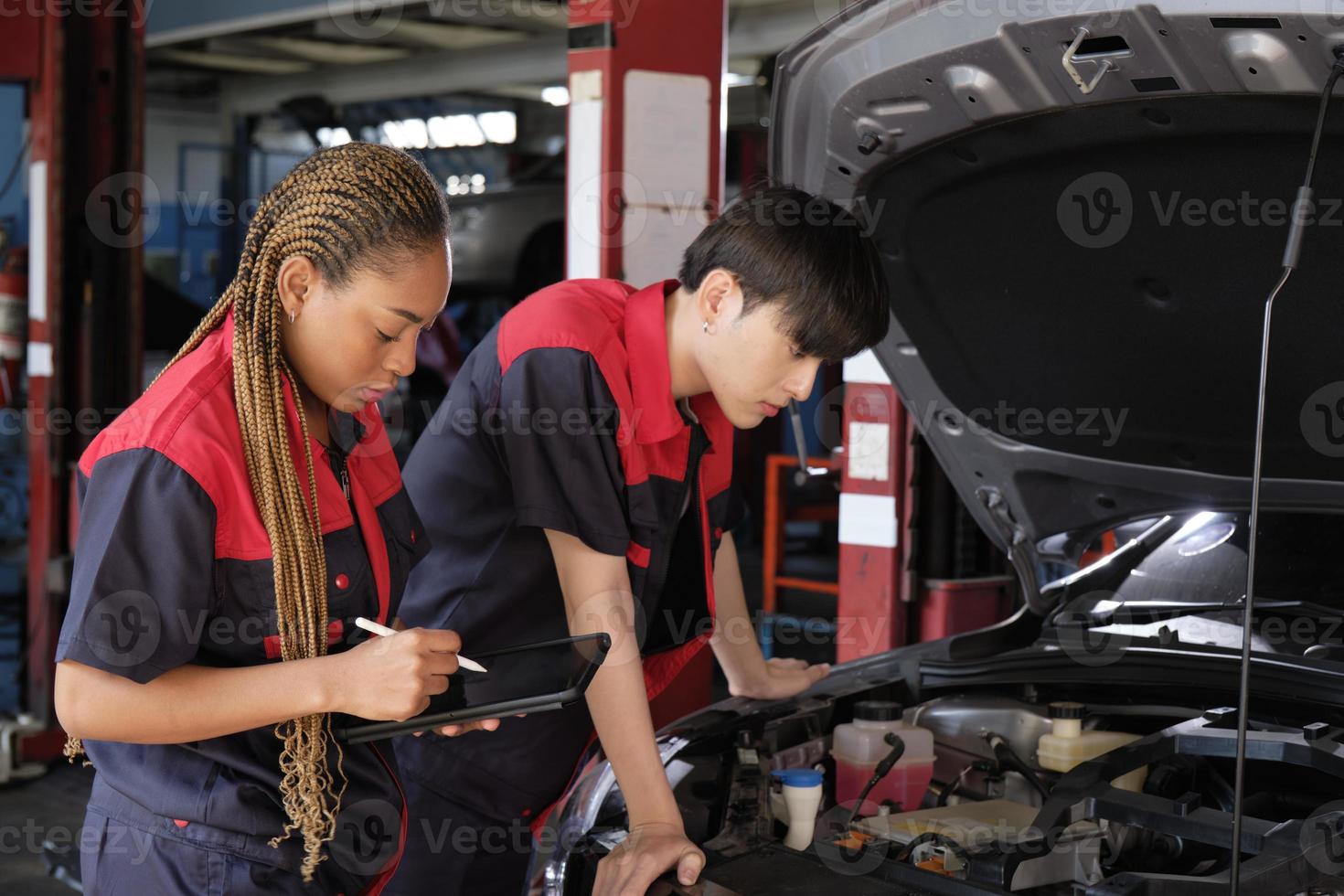 Two professional automotive mechanical partners check and repair an EV car battery and hybrid engine at a maintenance garage, expert electric vehicle service, and fixing occupations auto industry. photo