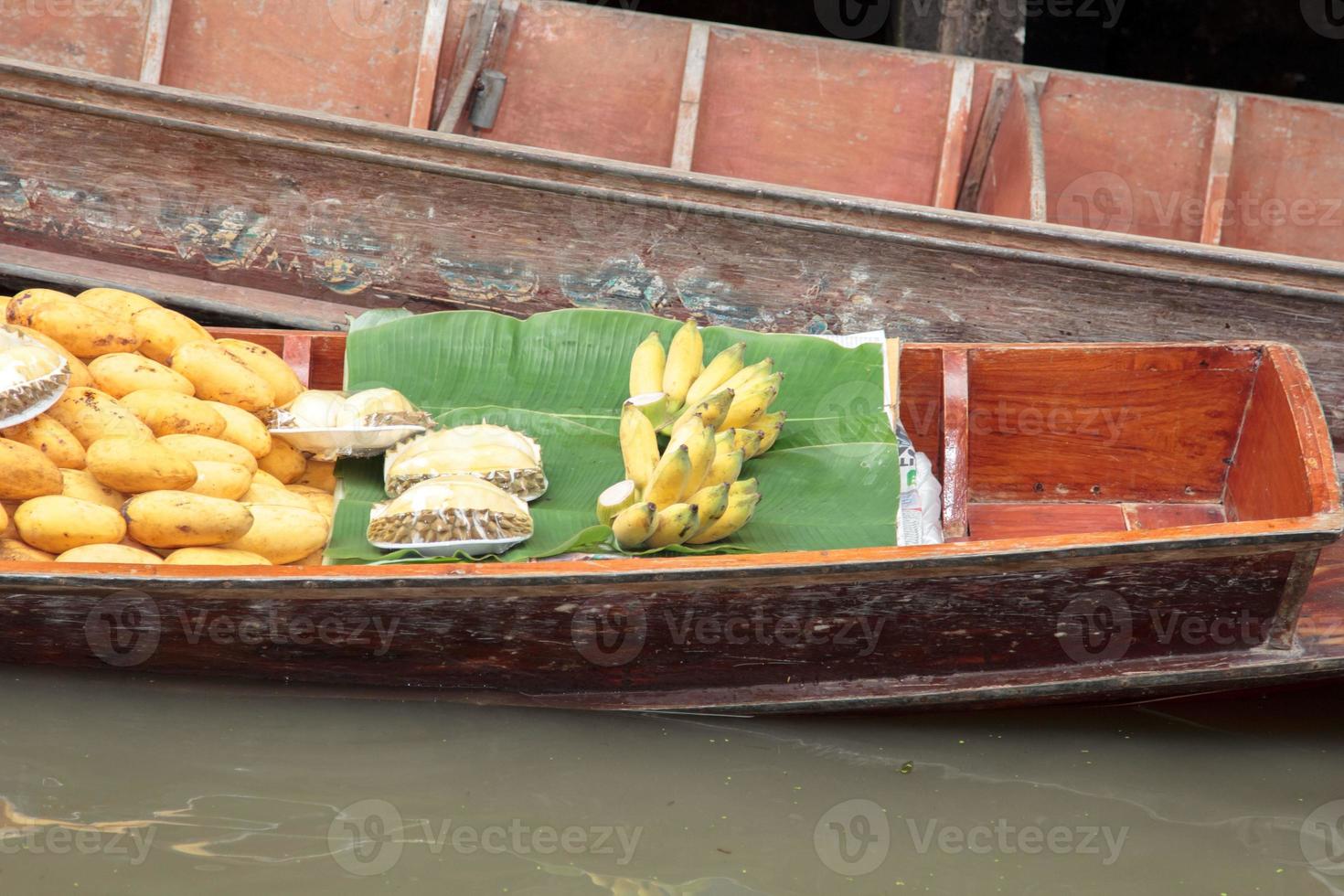 Boats selling fruit - ripe mango - in Damnoen Saduak Floating Market is a popular tourist destination that Europeans and Chinese like to travel with the traditional way of life of the villagers. photo