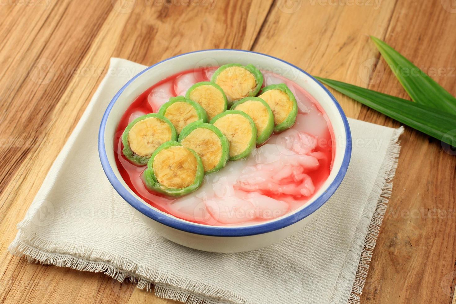 Es Pisang Ijo, Ripe Banana Rolled with Green Thin Crepes, Rice Porridge and Red Syrup. photo