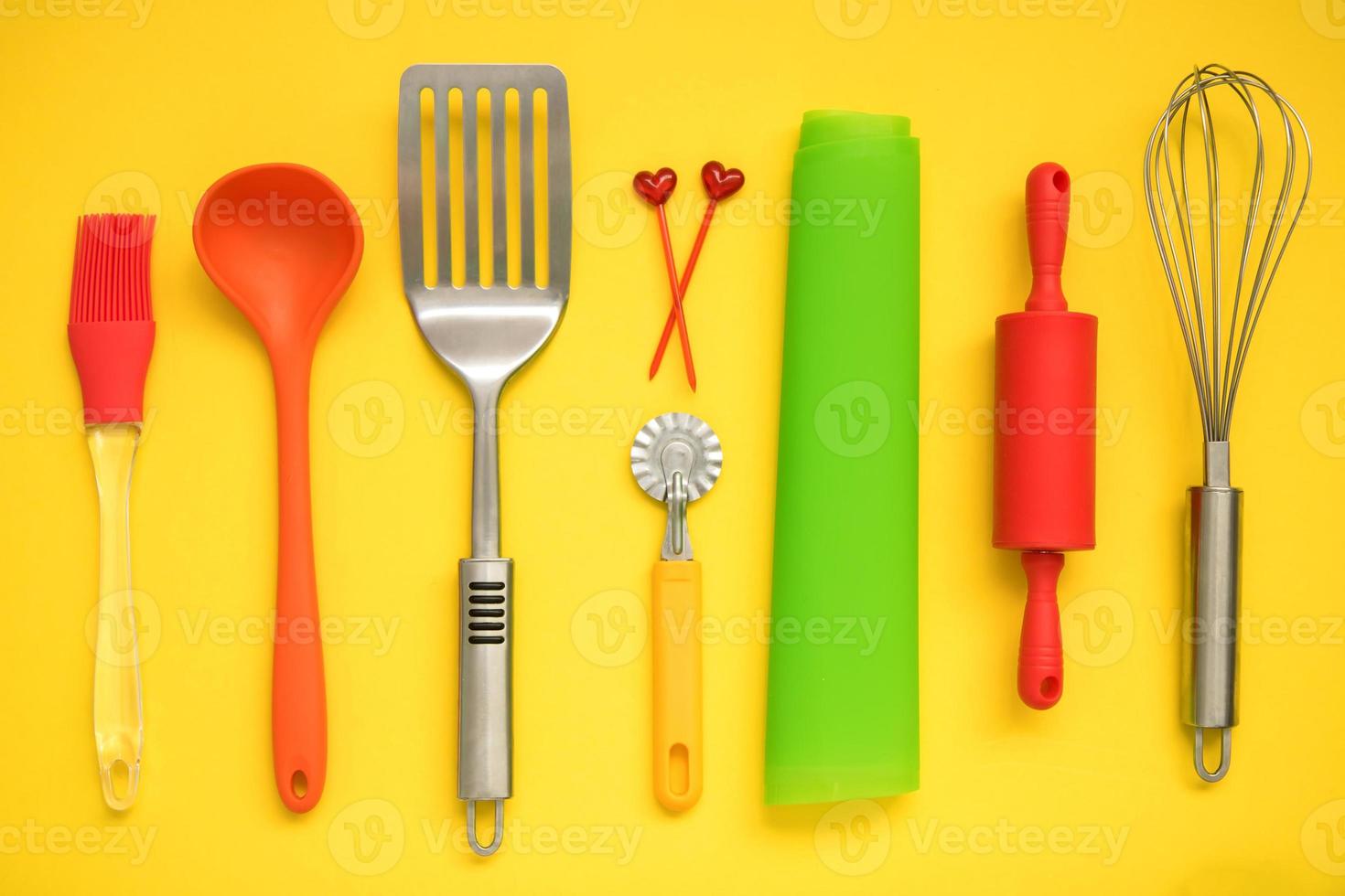 culinary background, culinary accessories on a yellow background - slotted spoon, dough knife, spatula, whisk, brush, skewers, silicone mat, rolling pin, ladle photo