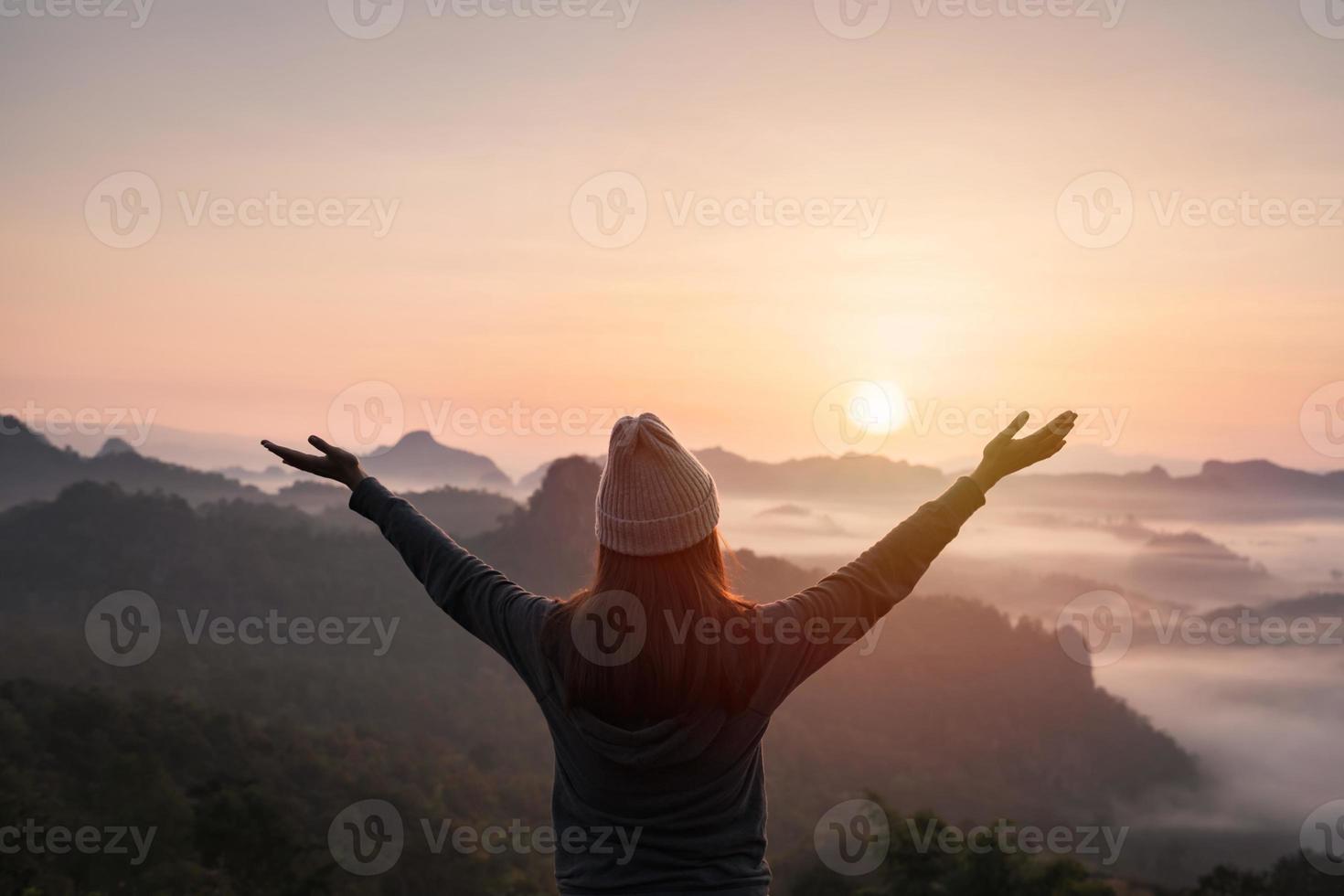 Young woman traveler looking at sea of mist and sunset over the mountain photo
