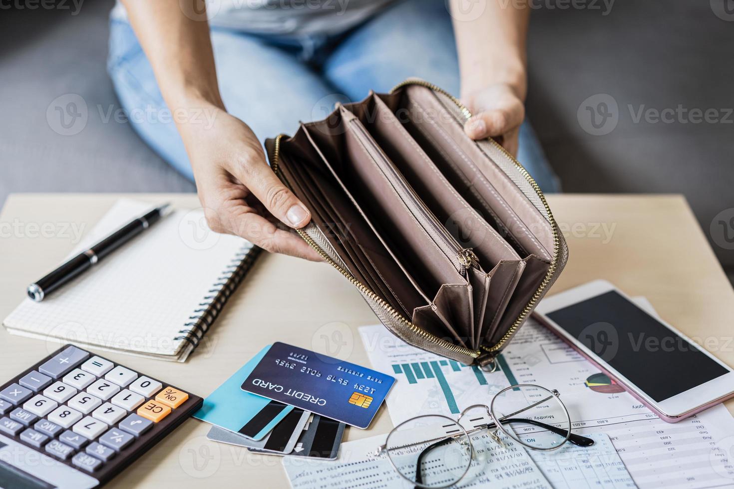 Stressed young woman open her empty wallet and calculating expenses at home photo