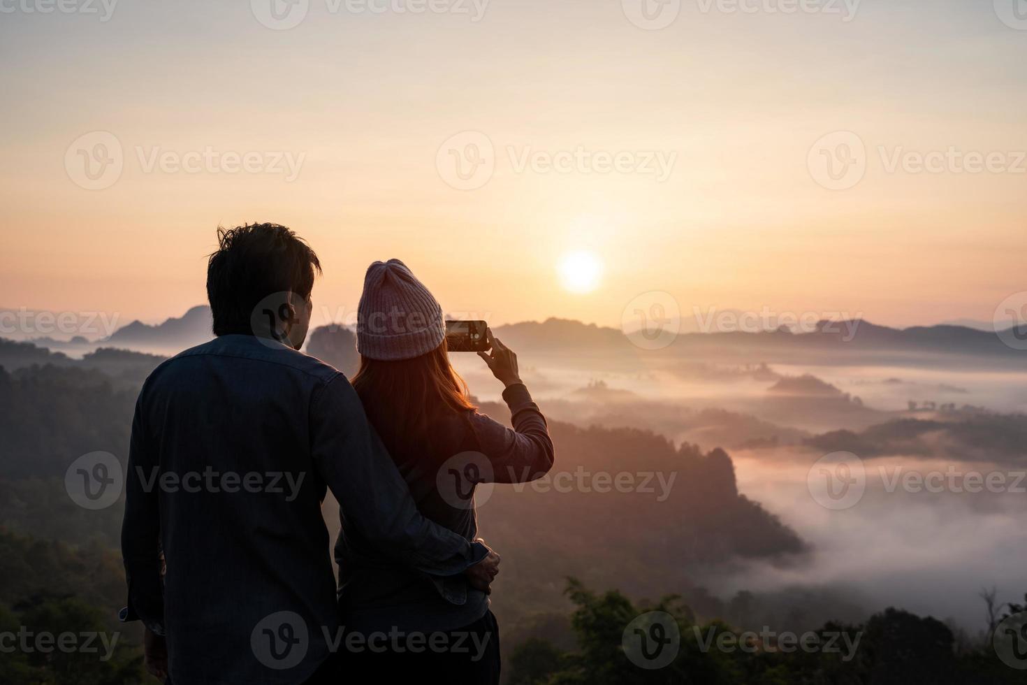 joven pareja viajera mirando el mar de niebla y la puesta de sol sobre la montaña en mae hong son, tailandia foto