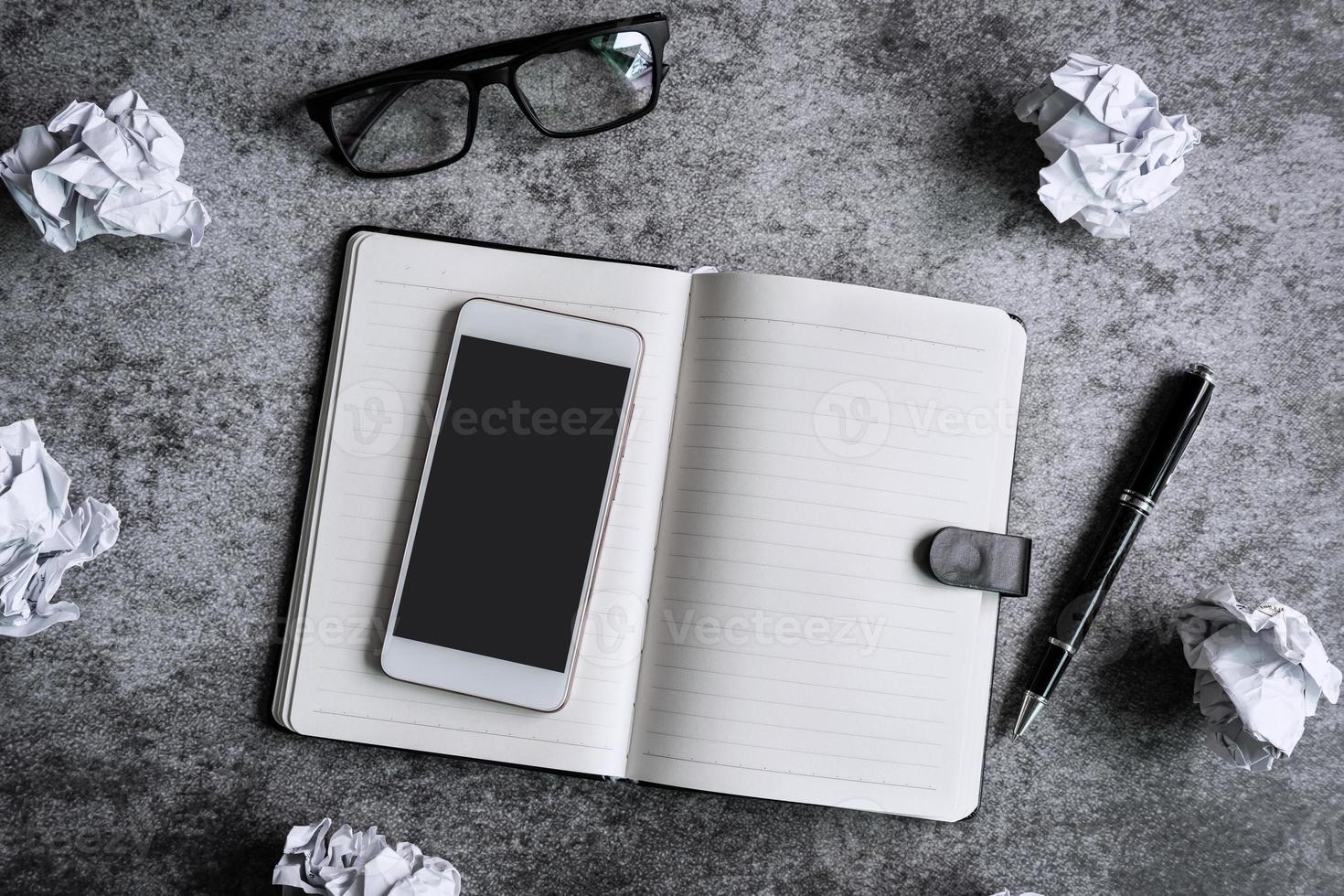 Crumpled paper balls with notebook and smartphone on desk office, Creativity problems concept photo