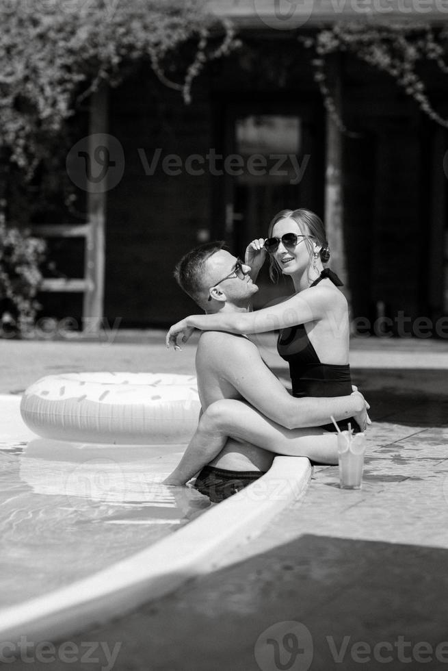 chico y un niña en baños trajes son relajante, cerca el azul piscina foto