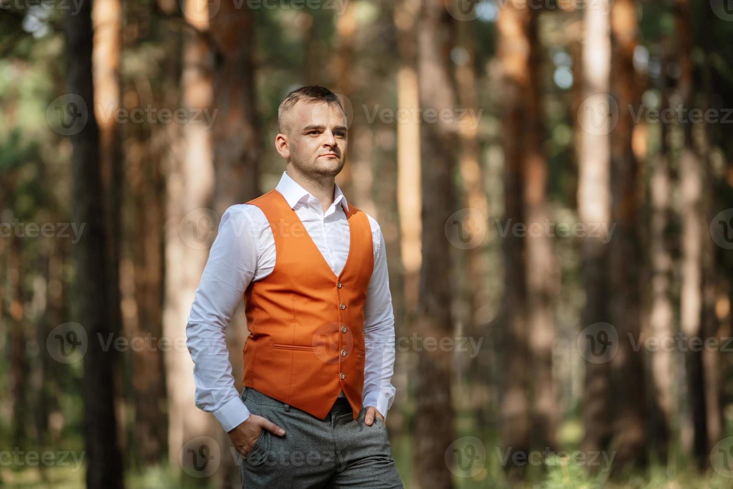 portrait of the groom in a gray suit and an orange vest photo