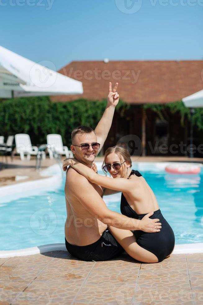 chico y un niña en baños trajes son relajante, cerca el azul piscina foto