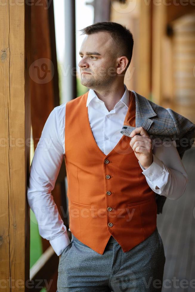 portrait of the groom in a gray suit and an orange vest photo