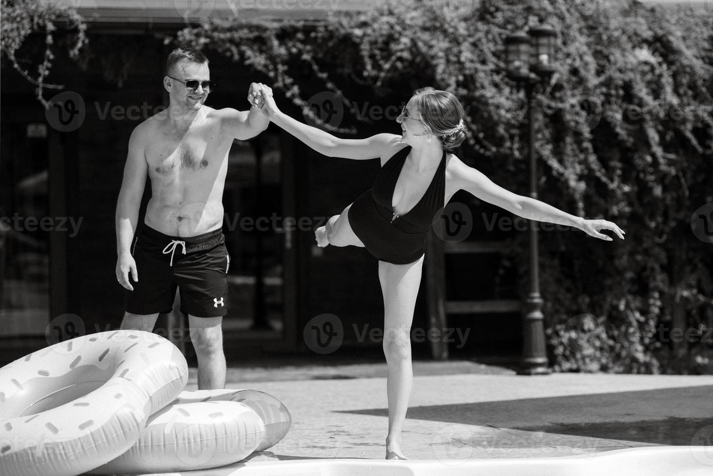 guy and a girl in bathing suits are relaxing, near the blue pool photo