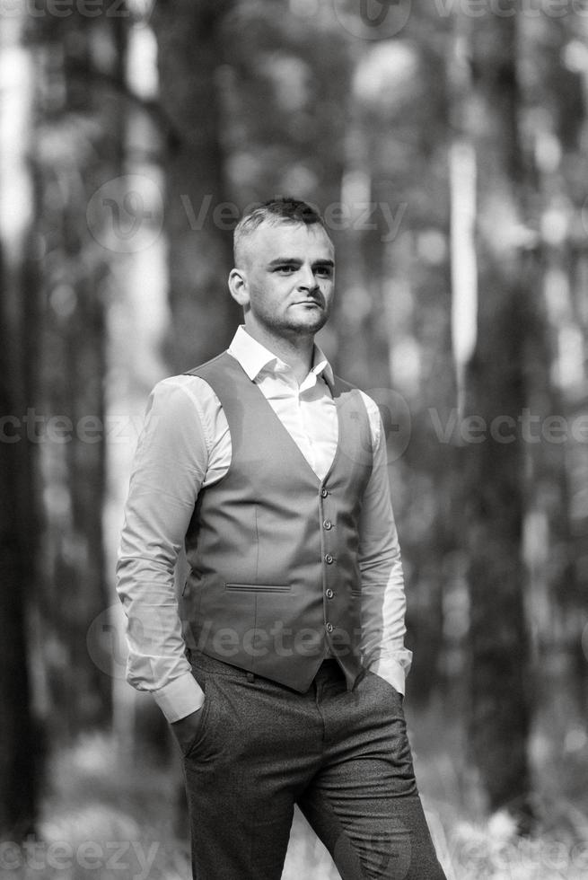 portrait of the groom in a gray suit and an orange vest photo