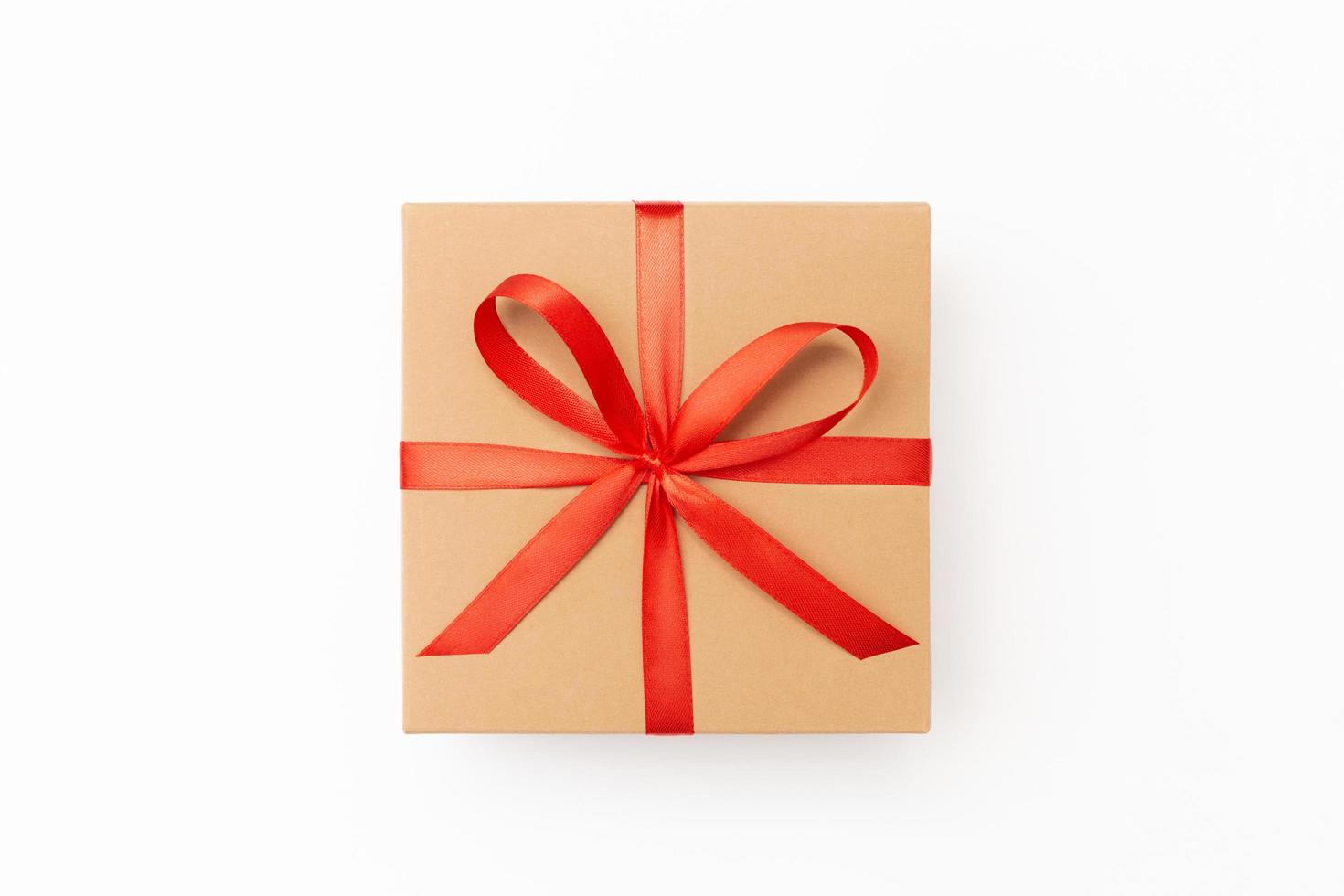 Flat lay of craft present box with red ribbon on the white background photo