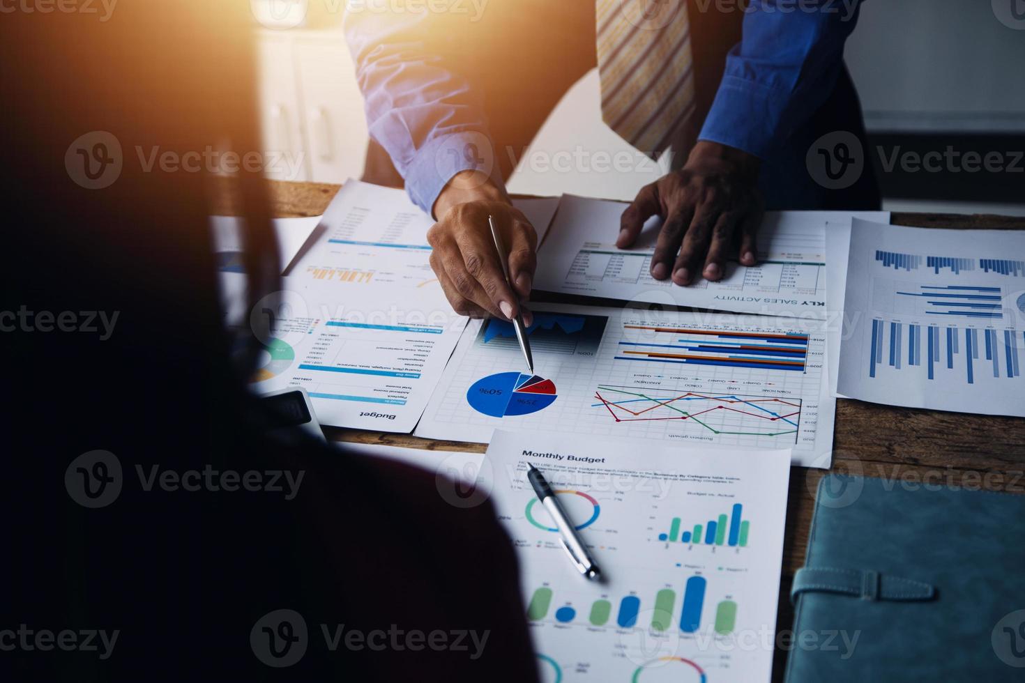 Group of confident business people point to graphs and charts to analyze market data, balance sheet, account, net profit to plan new sales strategies to increase production capacity. photo