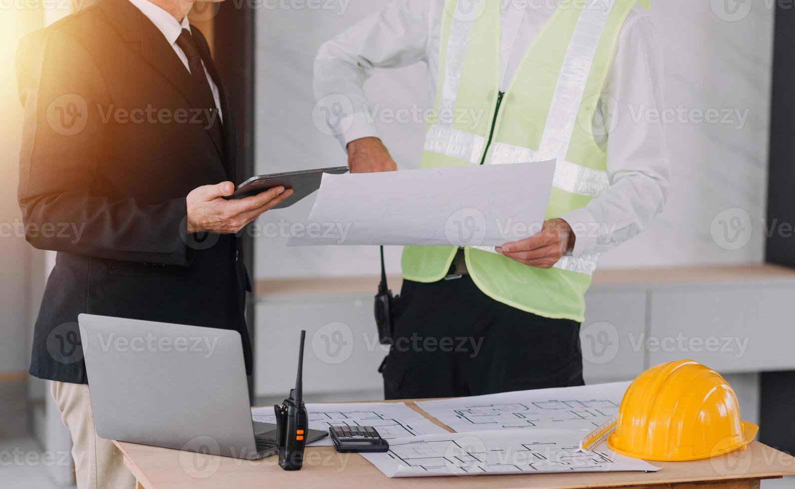 Two business man construction site engineer. Engineering objects on workplace with partners interacting on background photo