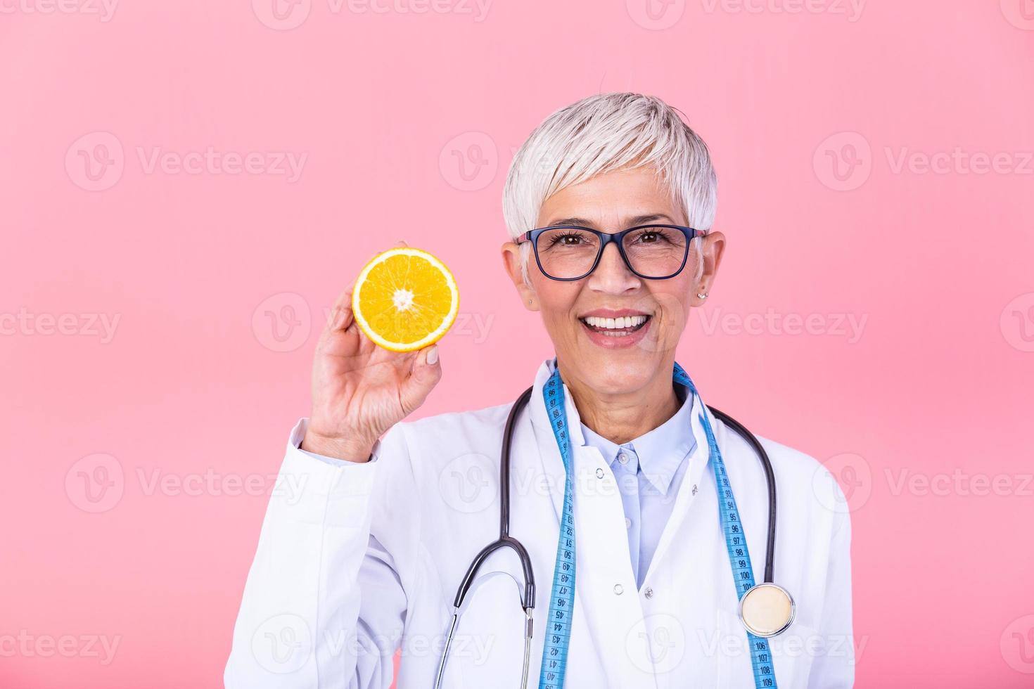 Smiling nutritionist holding a sliced orange, vitamins and healthy diet concept. Nutritionist with healthy fruit, juice and measuring tape. Dietitian working on diet plan. photo