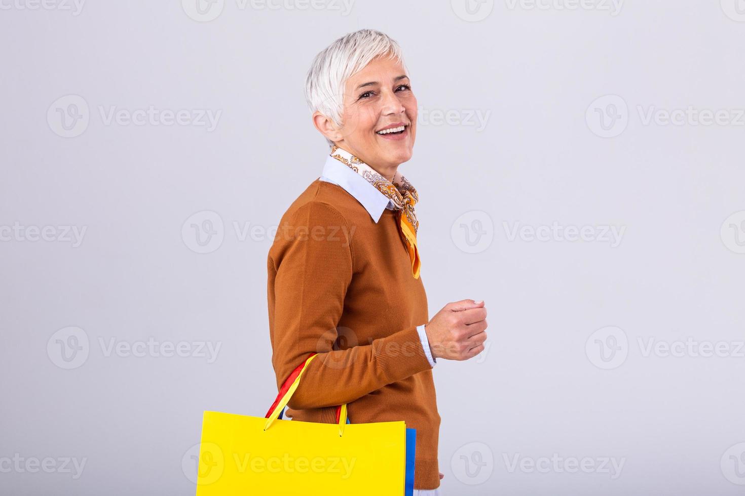 retrato de un contento maduro mujer participación compras pantalones y mirando a cámara aislado terminado blanco antecedentes foto