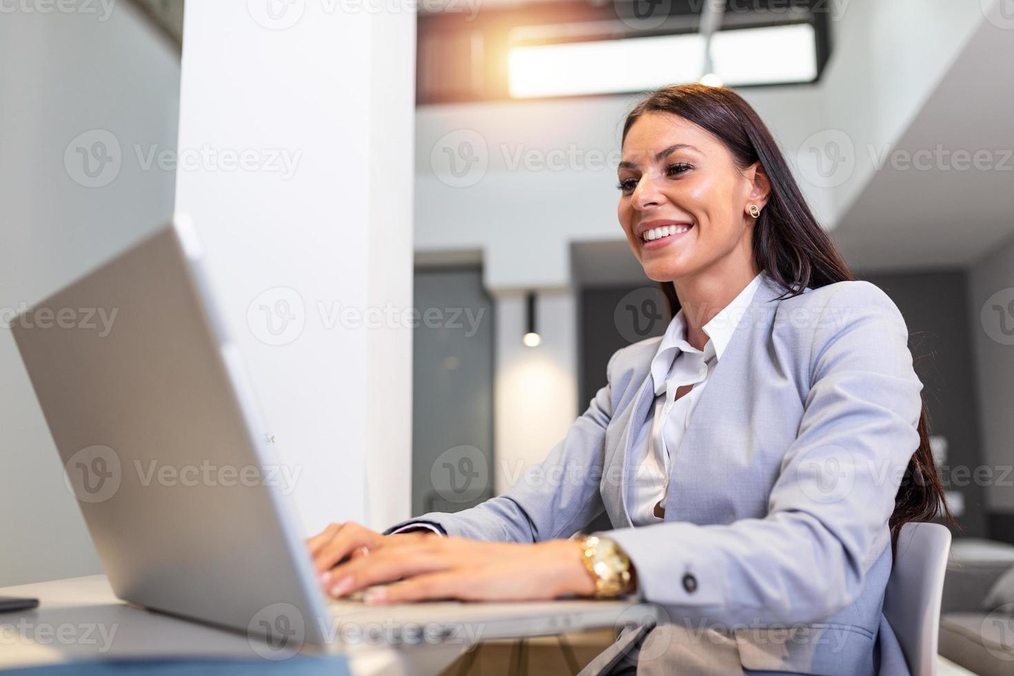 Young woman working from home, while in quarantine isolation during the Covid-19 health crisis. Portrait of a beautiful young business woman smiling and looking at laptop screen photo