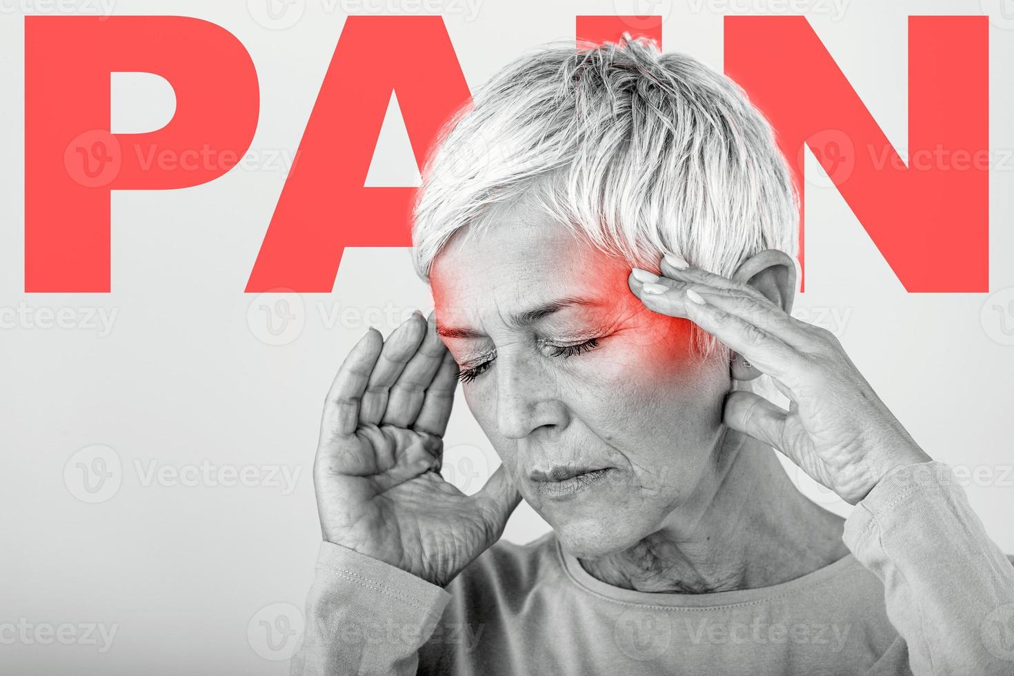 Woman suffering from stress or a headache grimacing in pain. Senior woman with migraine feeling unwell. Portrait of an attractive senior woman with a headache, feeling pain photo