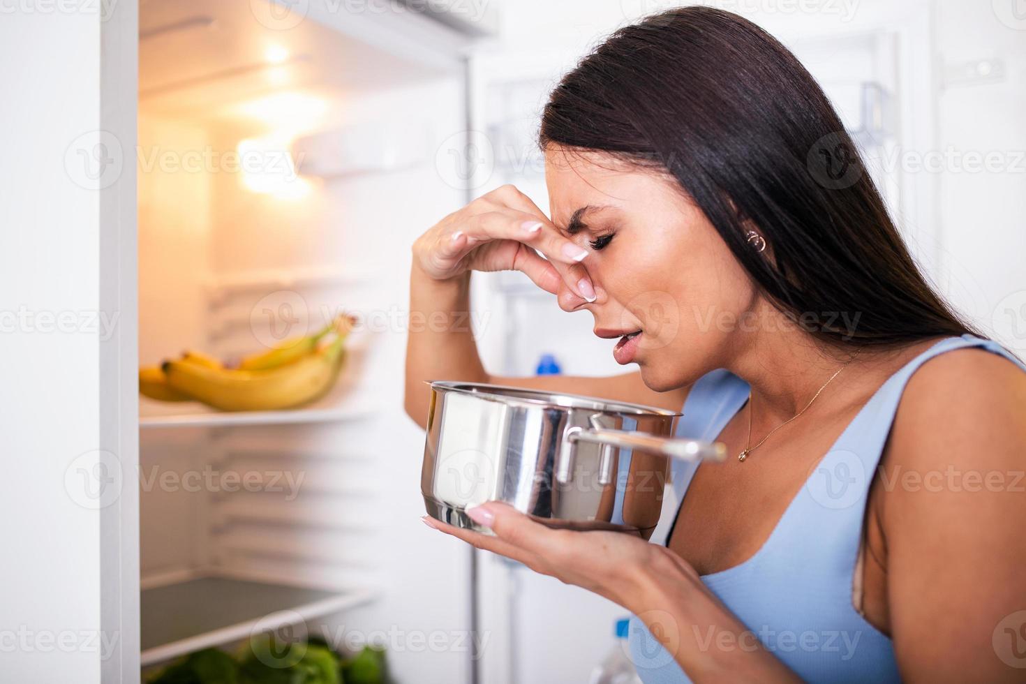Bad Food In Fridge, young woman in holding her nose because of bad