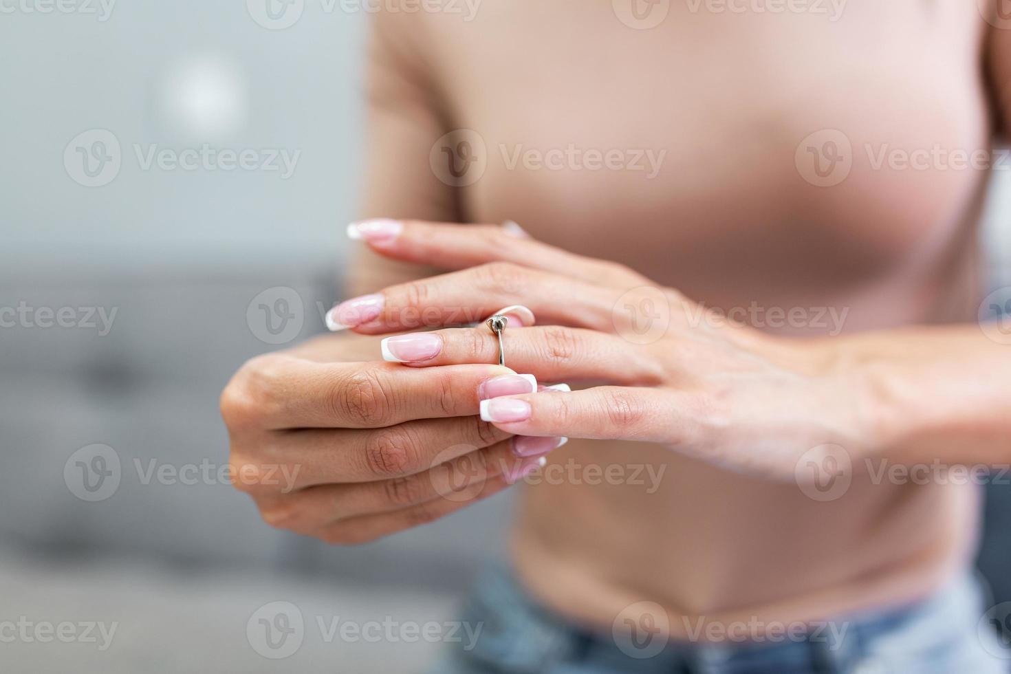 Young upset depressed lonely pensive divorced woman worrying about failed marriage and remove the ring from the finger after break up relationship and divorce photo