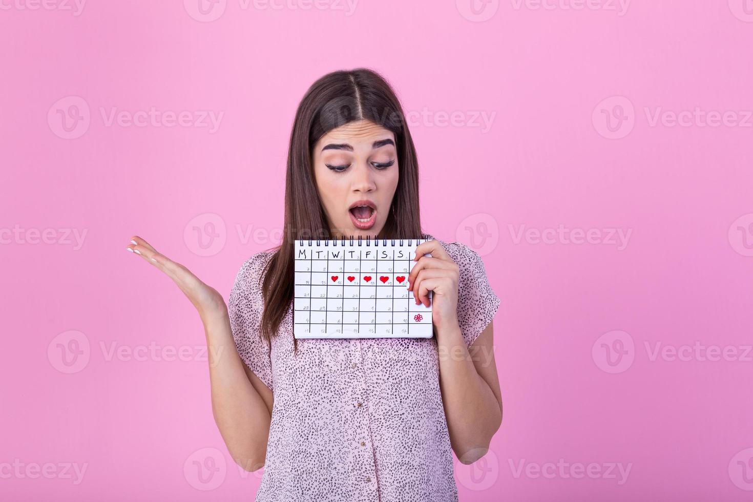 Young caucasian woman holding menstruation calendar over isolated background scared in shock with a surprise face, afraid and excited with fear expression photo