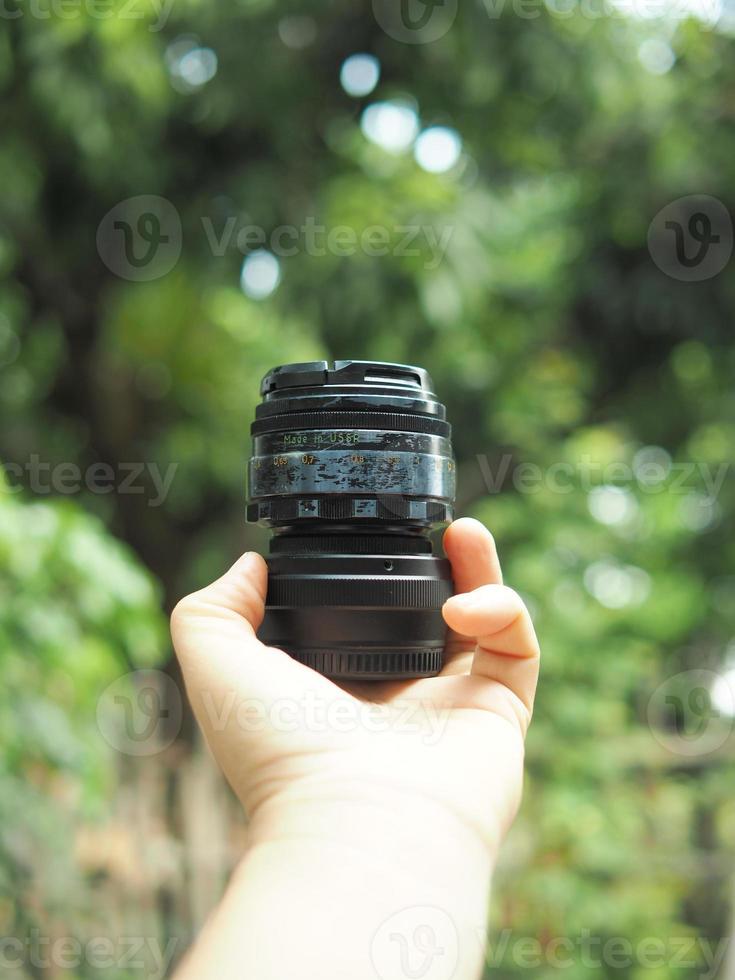 camera lens on hand with green nature background photo