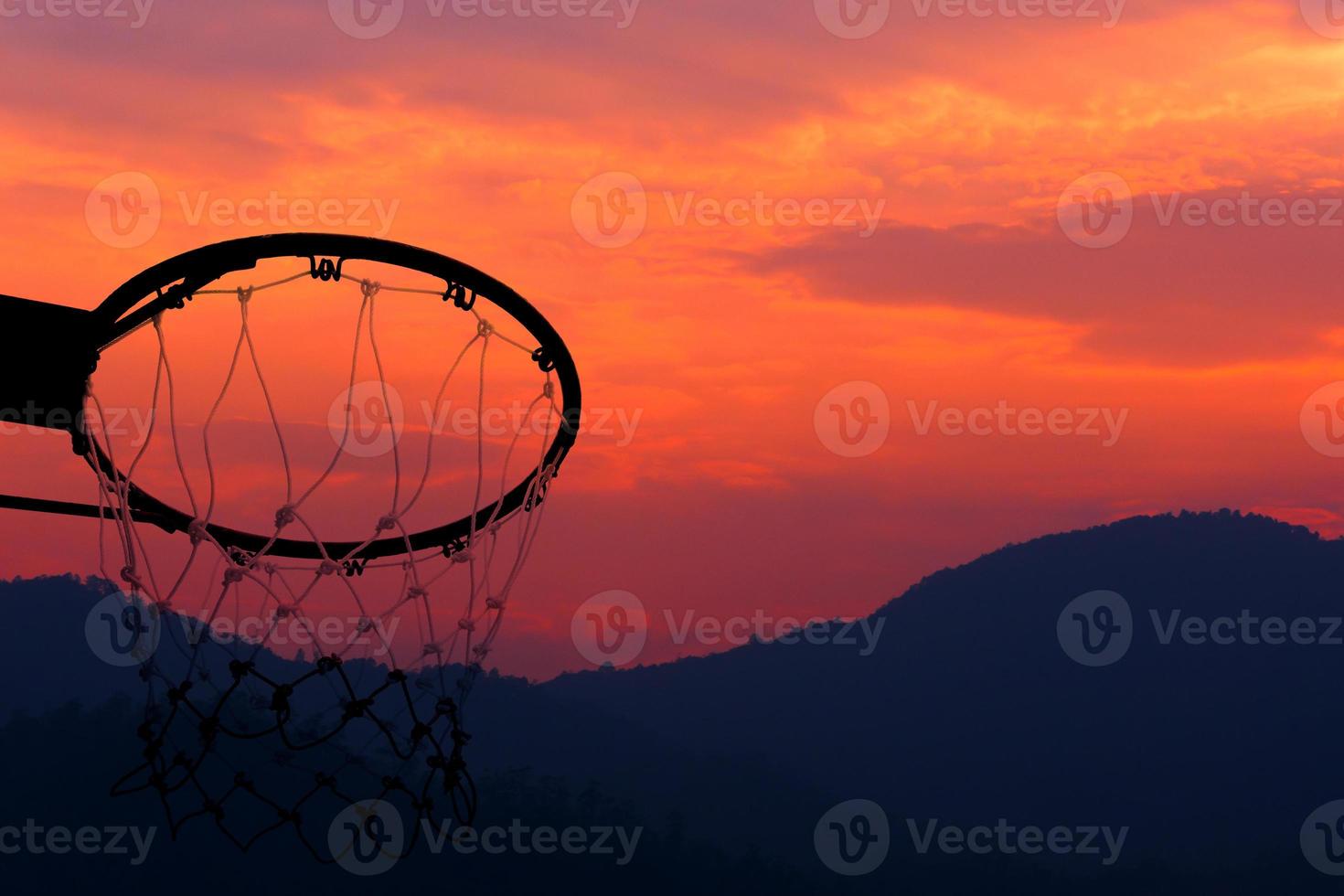 Basketball hoop viewed from below on beautiful sunset background, A view of a basketball hoop from below photo