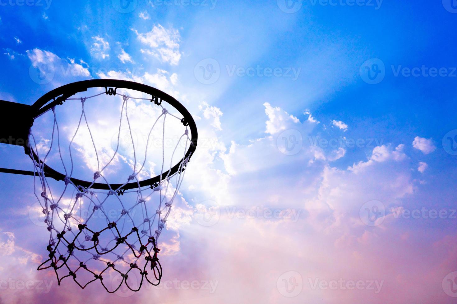 Basketball hoop viewed from below on beautiful sky background, A view of a basketball hoop from below photo