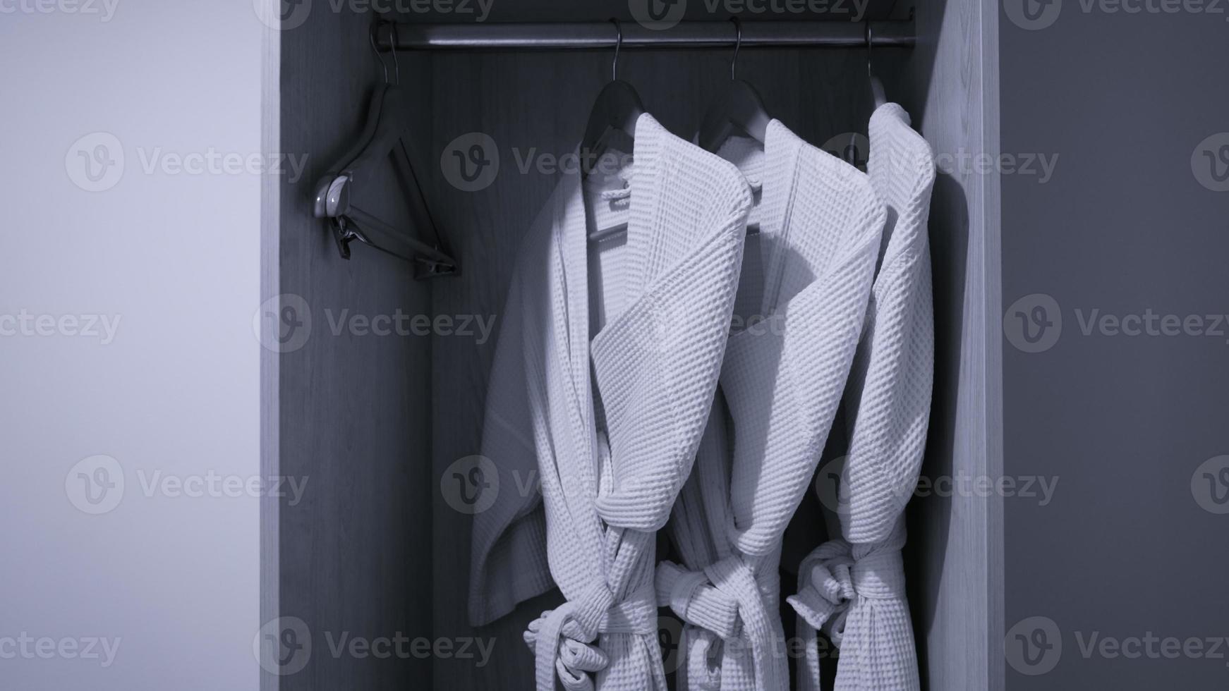 three bathrobe hanging on rack in wardrobe at hotel room photo