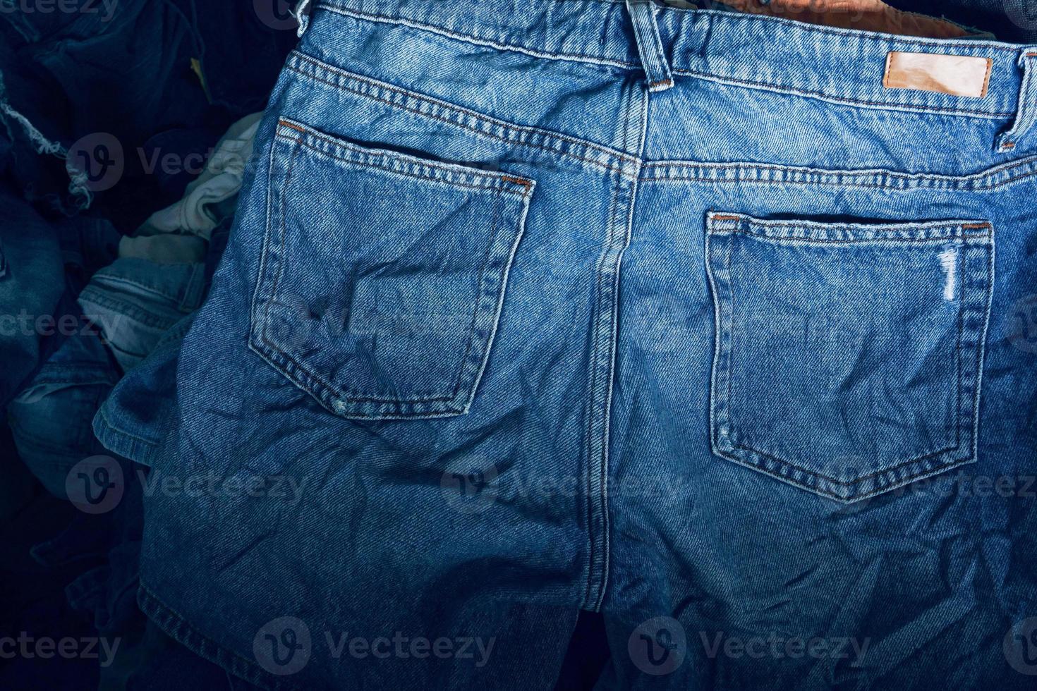 tela textura, cerca arriba de azul mezclilla vaquero textura con espalda bolsillo detalle..destruido Rasgado clásico mezclilla azul pantalones parches, bandera Moda antecedentes foto