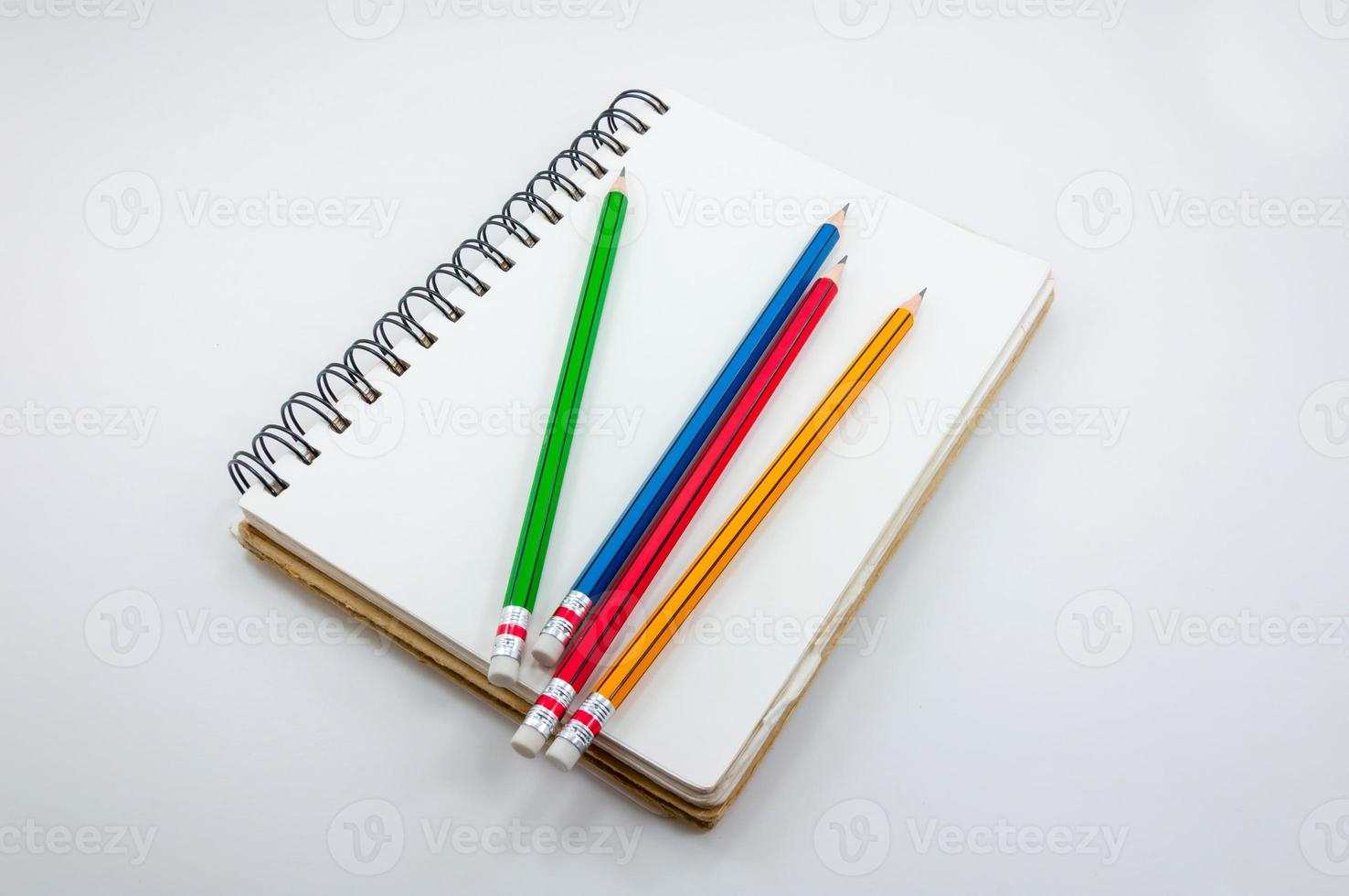 cuaderno y vistoso lápiz en blanco antecedentes foto