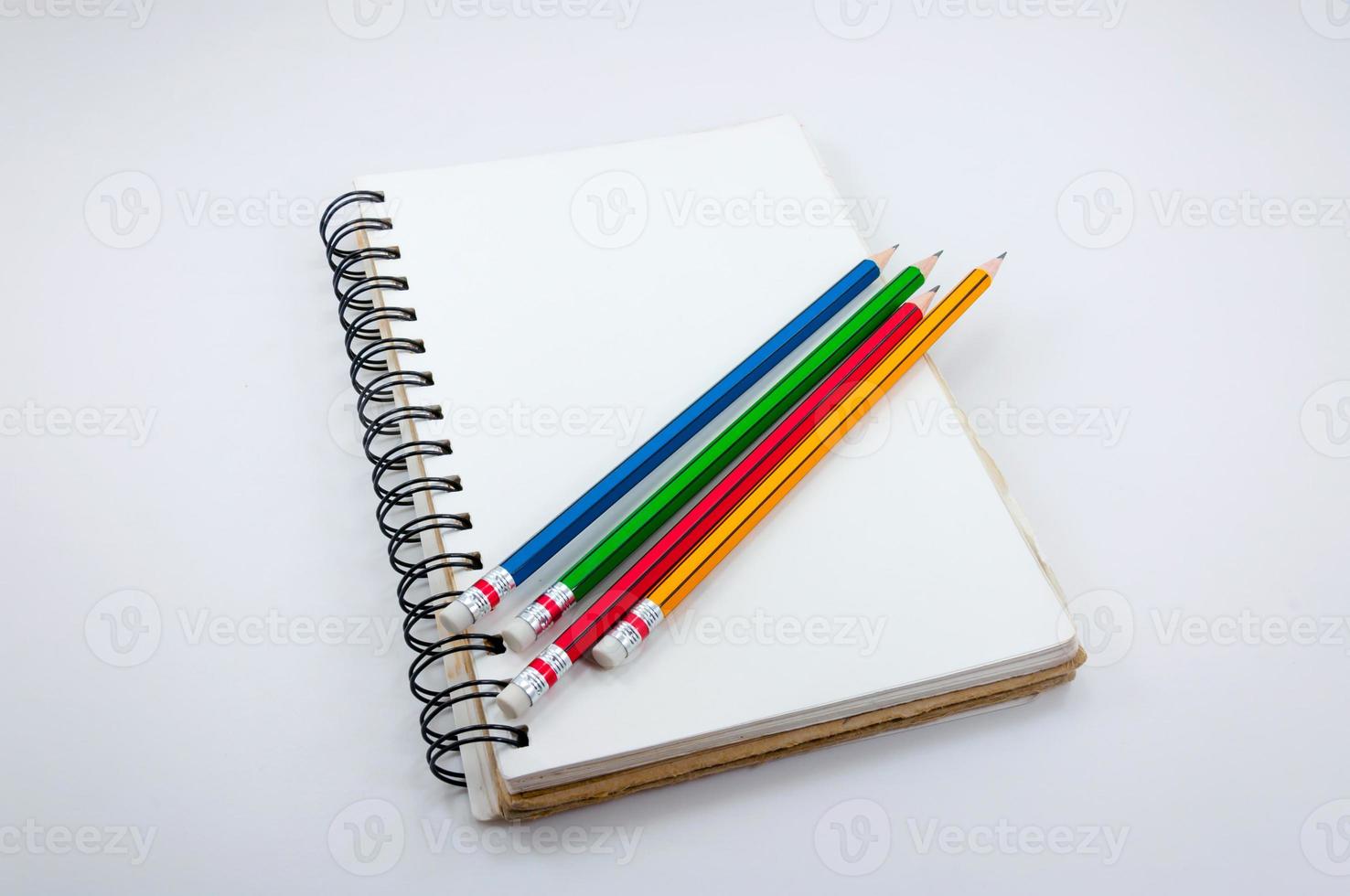 cuaderno y vistoso lápiz en blanco antecedentes foto