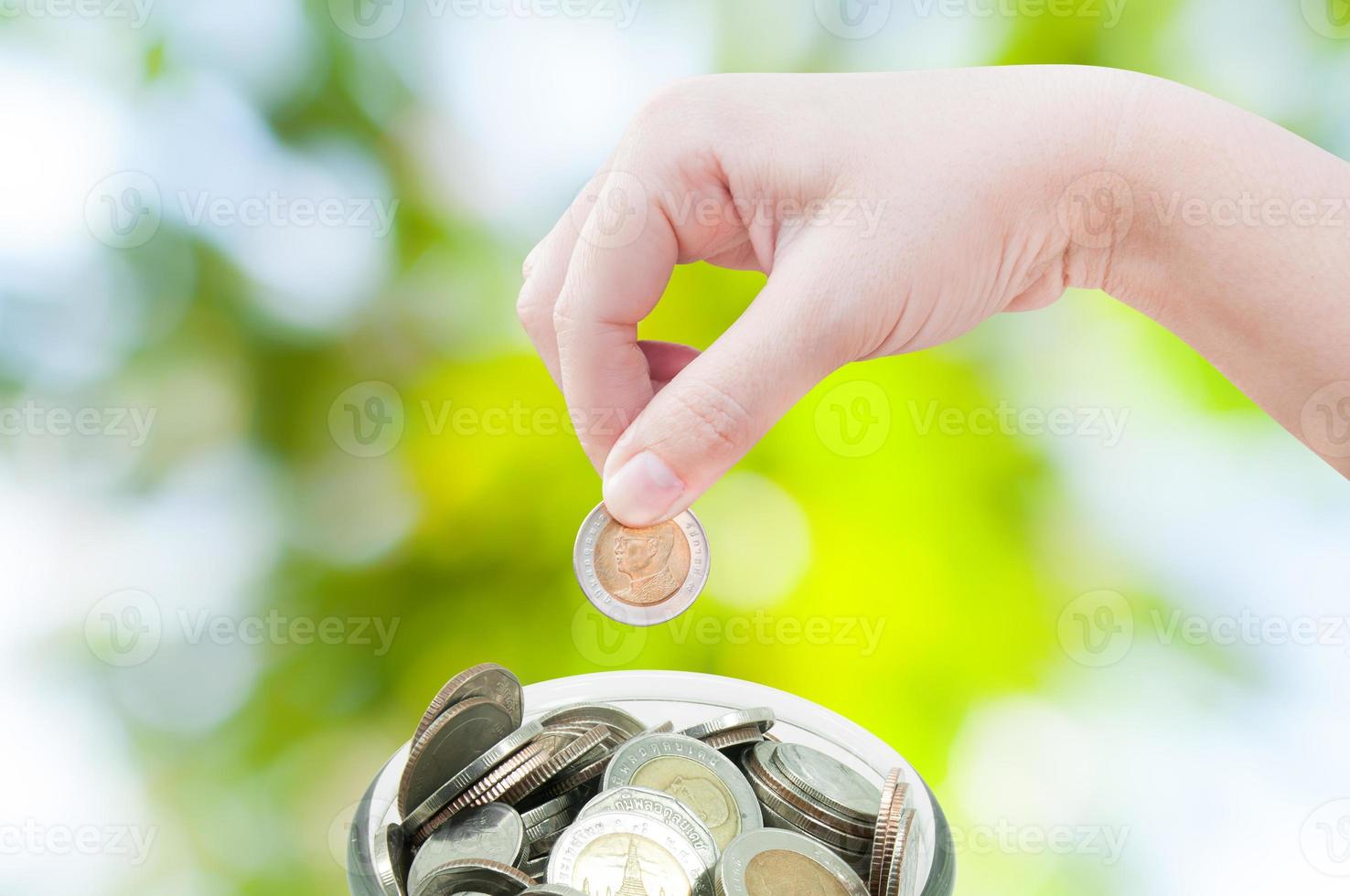 woman hand putting a coin on green nature background,saving ,Donation Investment Fund Financial Support Charity  Dividend Market Growth photo