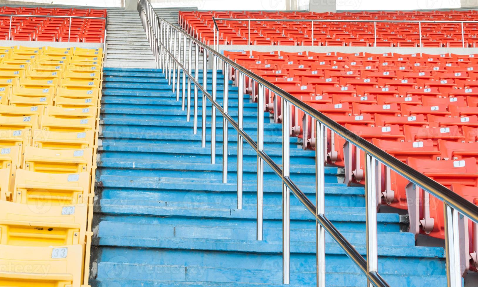 asientos vacíos de color naranja y amarillo en el estadio, filas de asientos en un estadio de fútbol foto