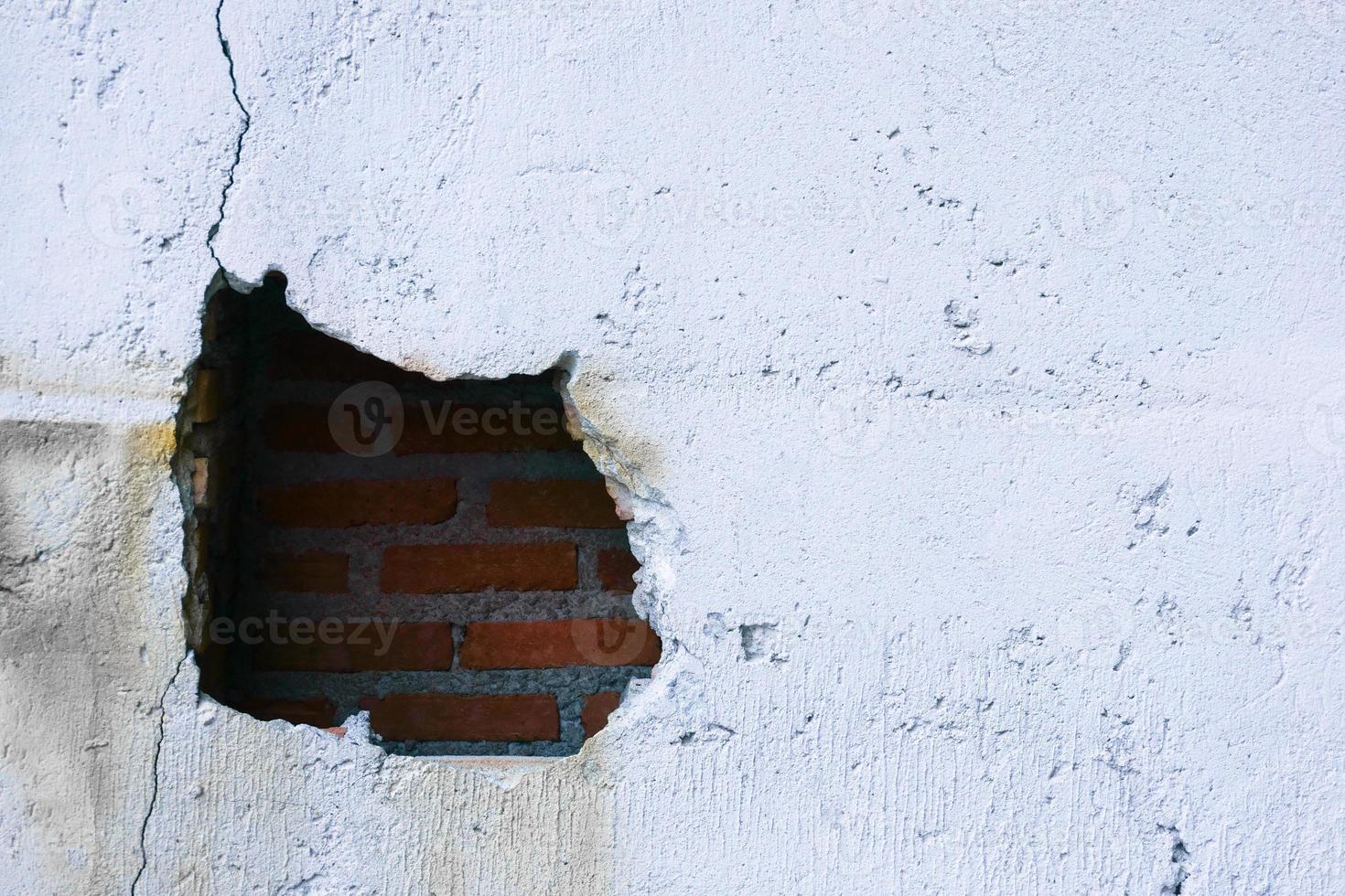 agujero en roto pared y antiguo ladrillos en blanco antecedentes. grande grieta en el pared de un antiguo ladrillo casa, desmoronándose yeso y roto, agrietado ladrillos foto