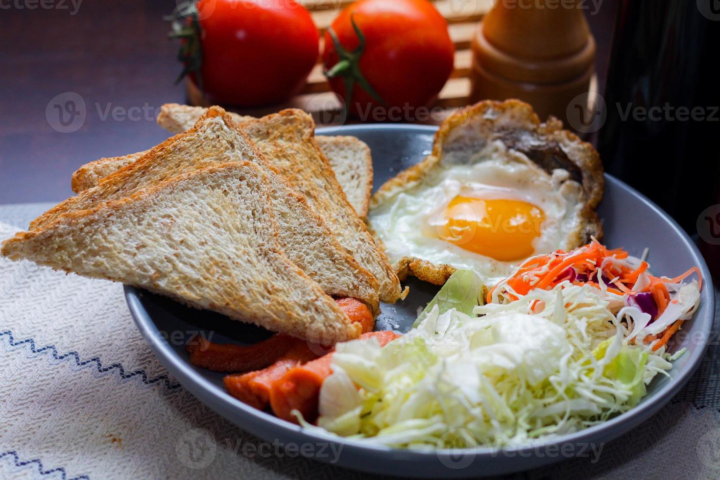 desayuno, frito huevos, frito embutido, vegetal ensalada y brindis en un marrón de madera mesa con café. foto