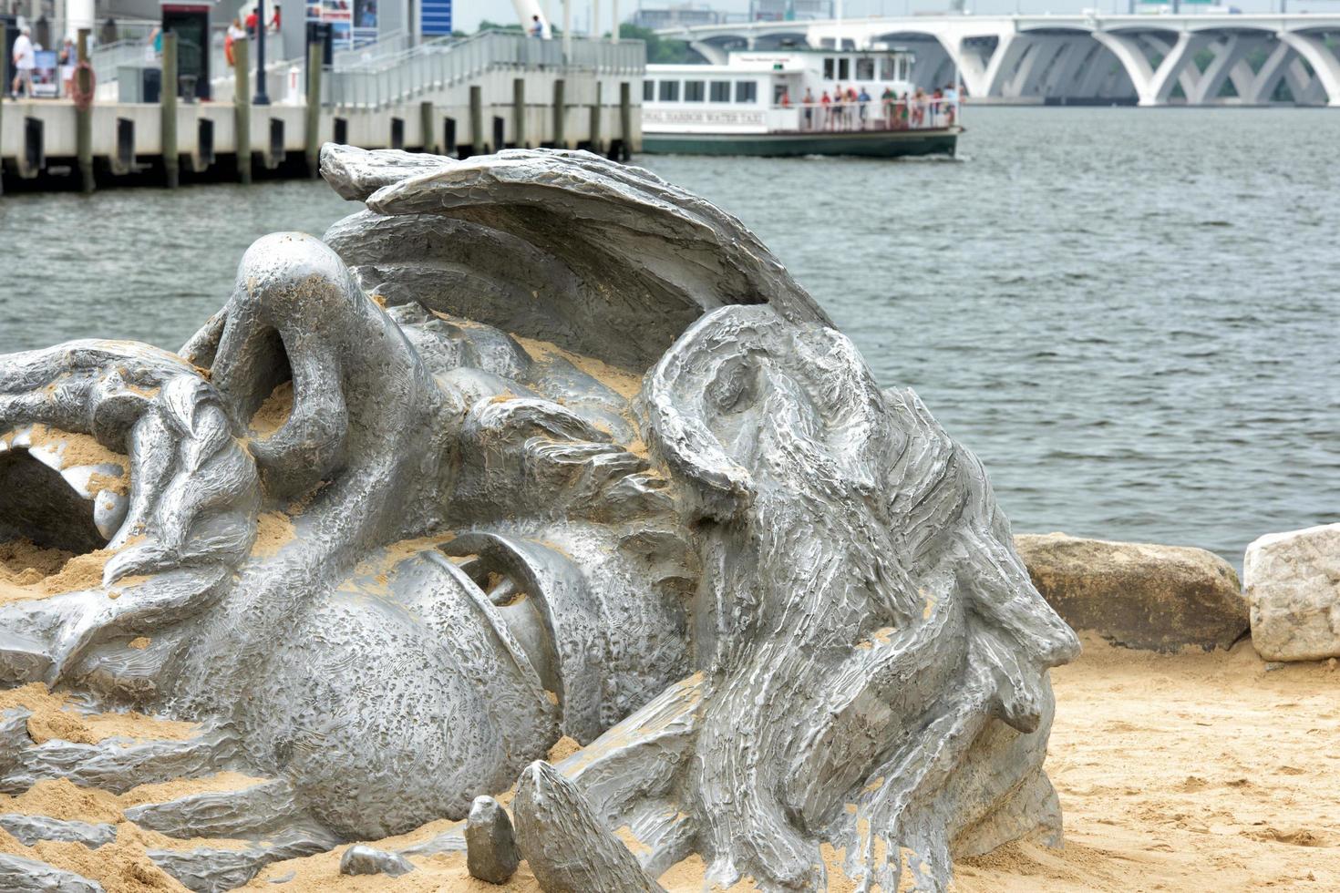 OXON HILL, MD - JUNE 19, 2015 Awakening Sculpture at National Harbor on August 24, 2013 at Oxon Hill, MD USA. A famous 70-foot statue of a giant embedded in the earth created by J. Seward Johnson Jr. photo