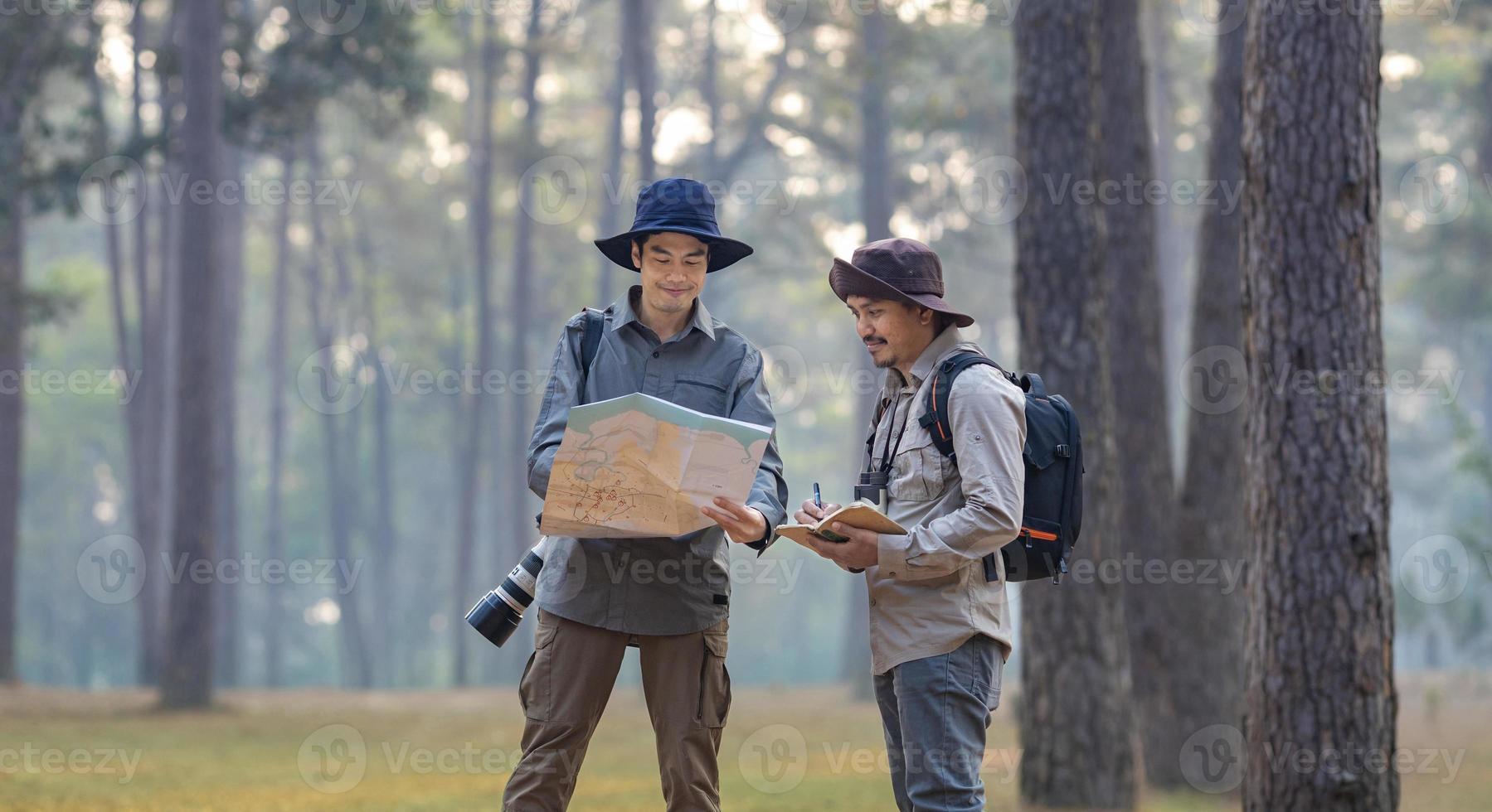 Team of the Asian naturalist looking at the map while exploring in the pine forest for surveying and discovering the rare biological diversity and ecologist on the field study concept photo