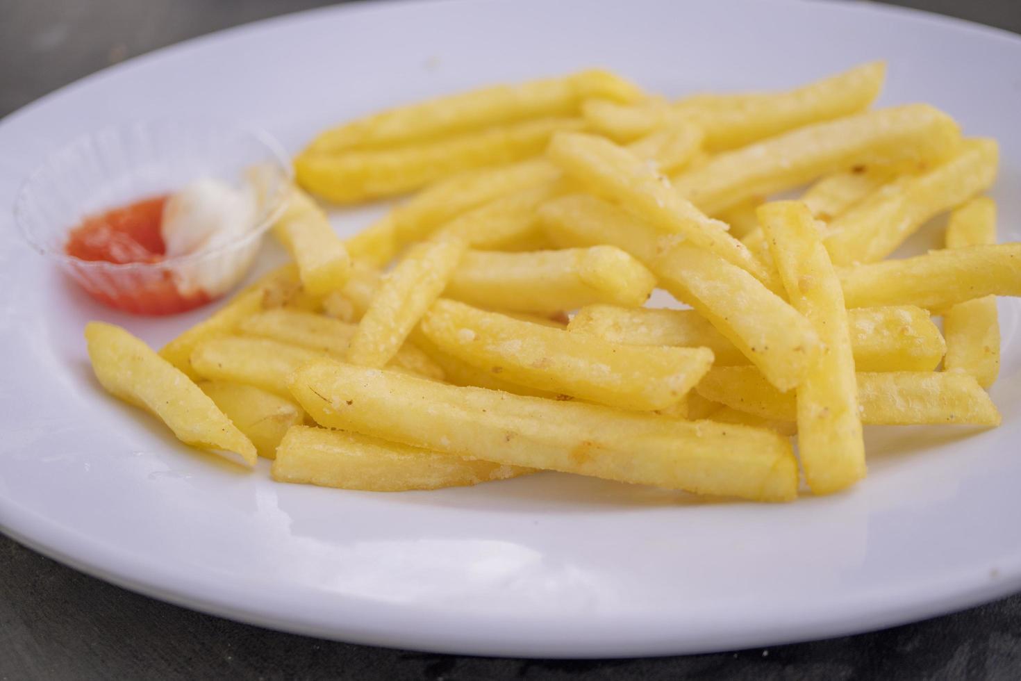 Close up photo of fried fries on white plate with mayo spicy sauce. The photo is suitable to use for Indonesia traditional food background, food poster and food content media.