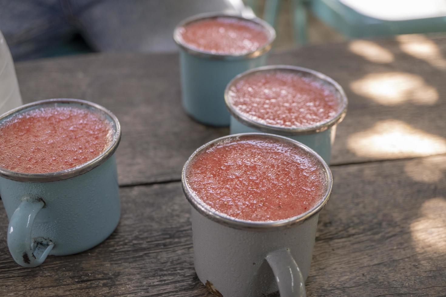 Close up photo of fresh strawberry juice on the blue cup at the garden shop. The photo is suitable to use for healthy drink, menu background, and drink content media.